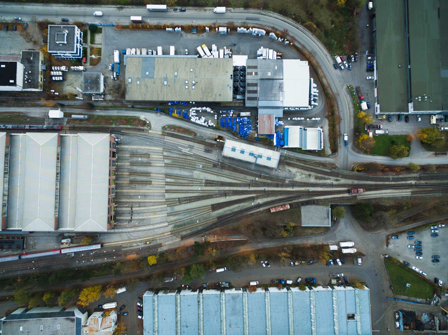 Aerial view of an industrial area with multiple railway tracks, warehouses, and surrounding roads.