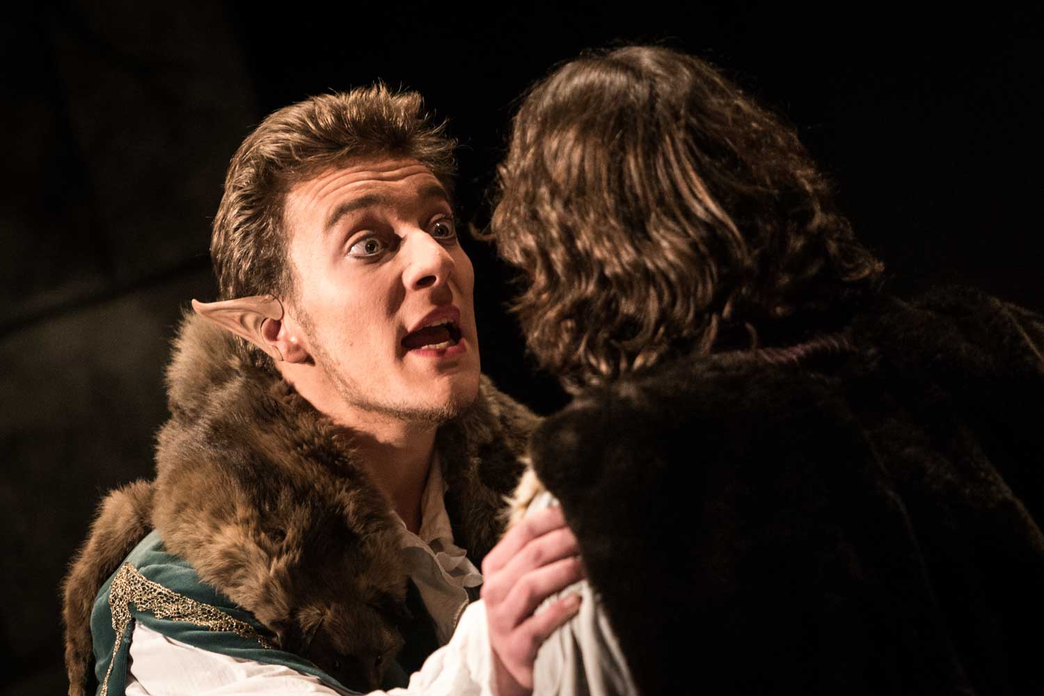 Actor with elf costume and pointed ears in intense dialogue on stage.
