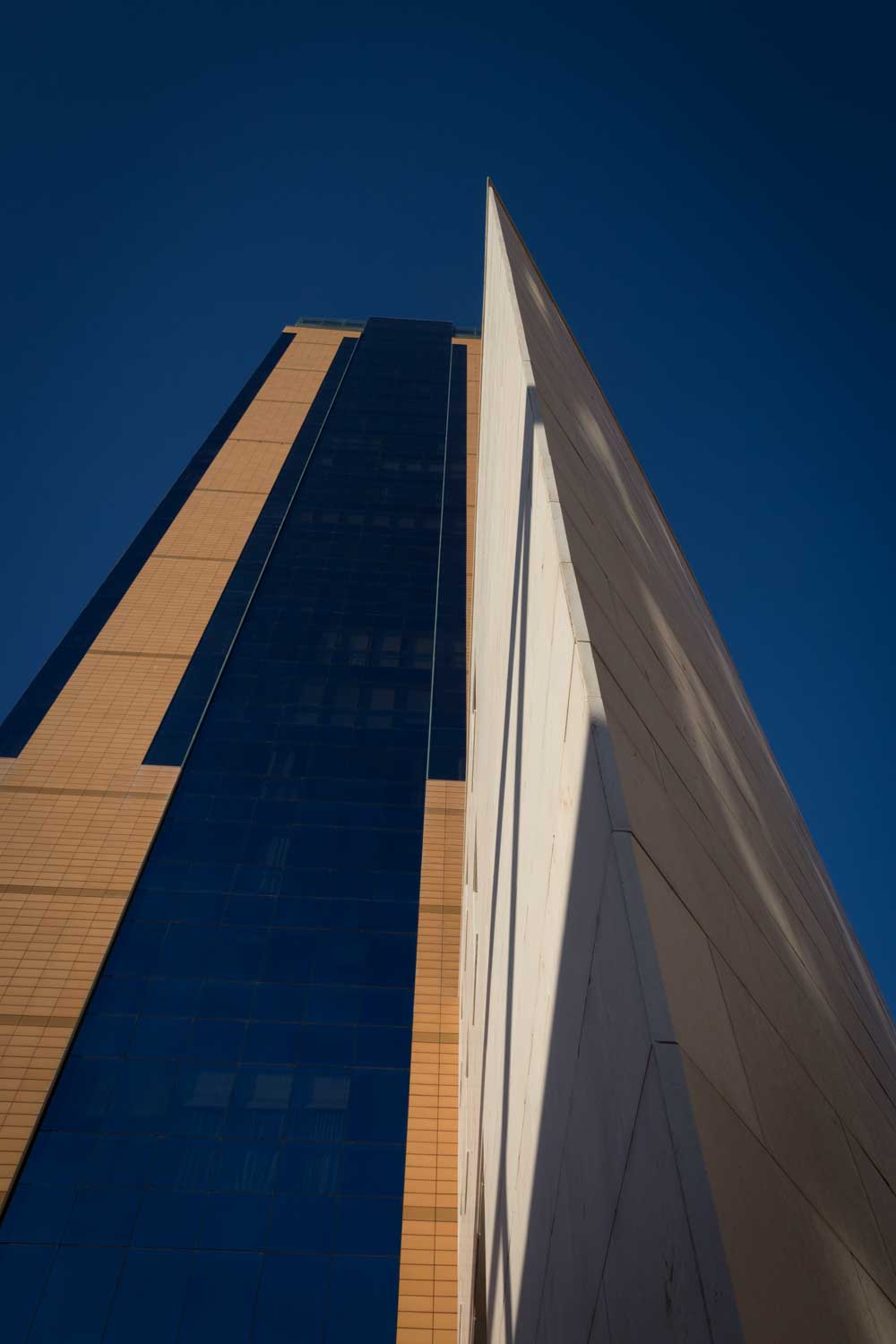 Modern skyscraper with glass and brick facade beneath clear blue sky.