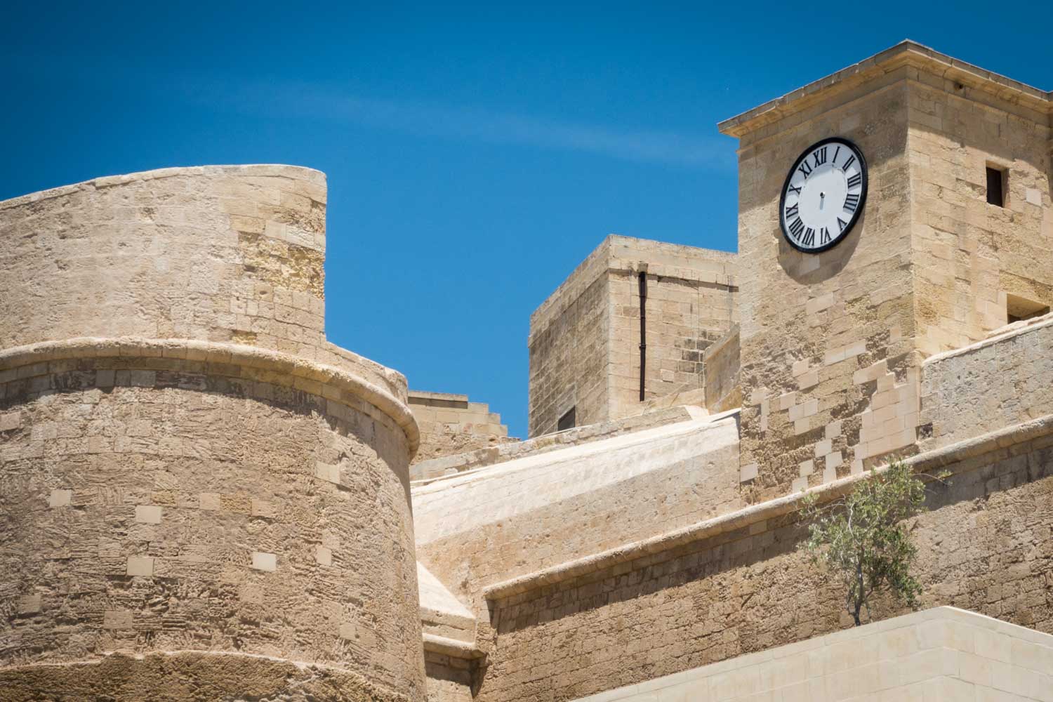Medieval stone tower with clock, under a clear blue sky, showcasing historic architecture.