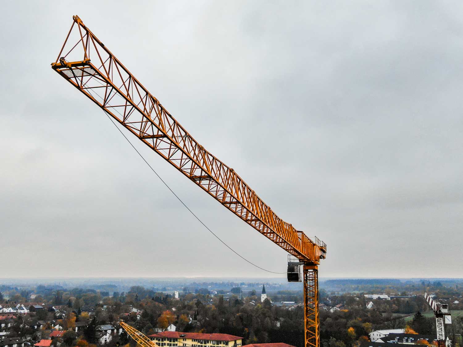 Yellow construction crane over a cloudy cityscape.