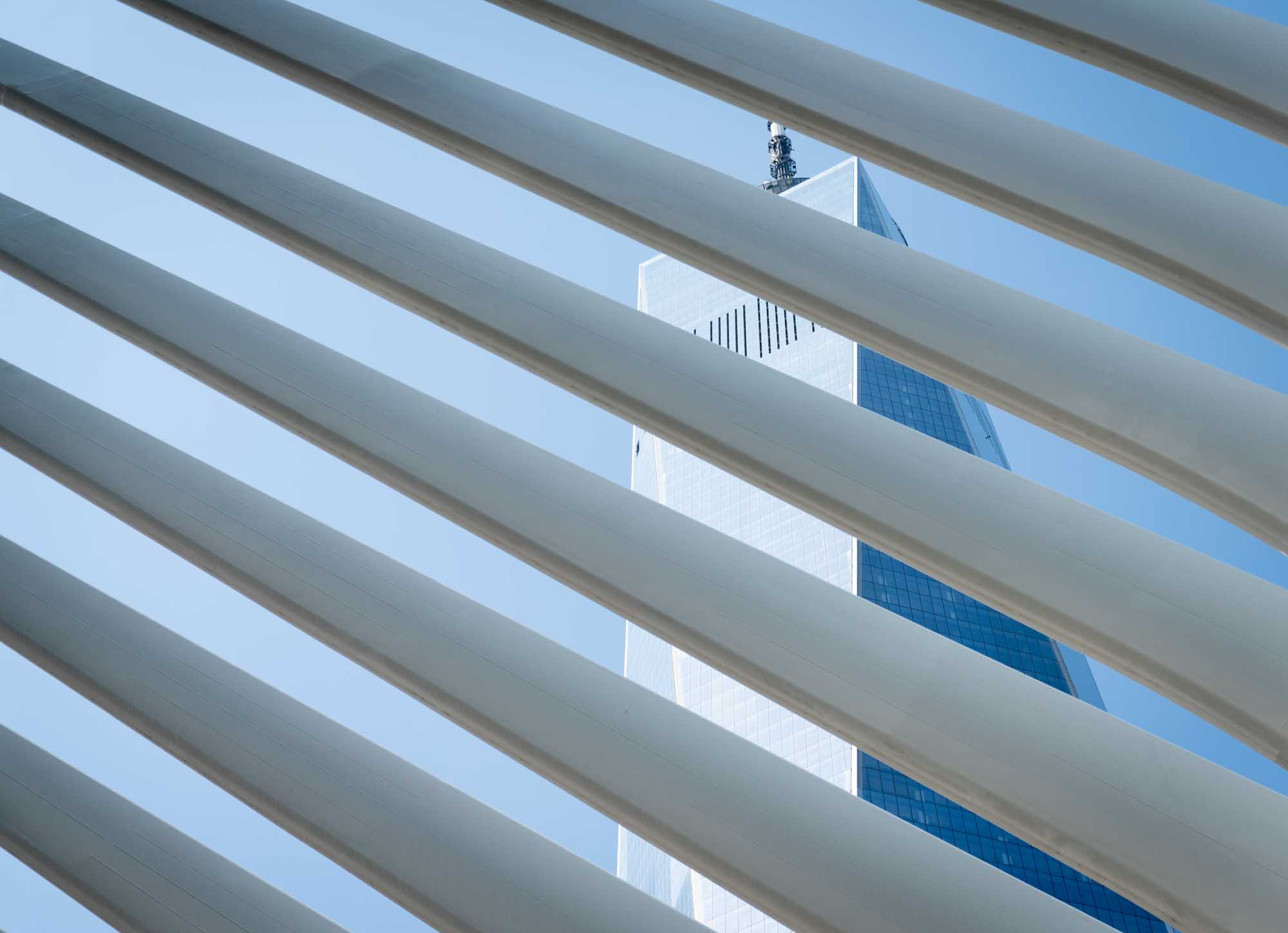 Tower seen through architectural beams against clear blue sky.