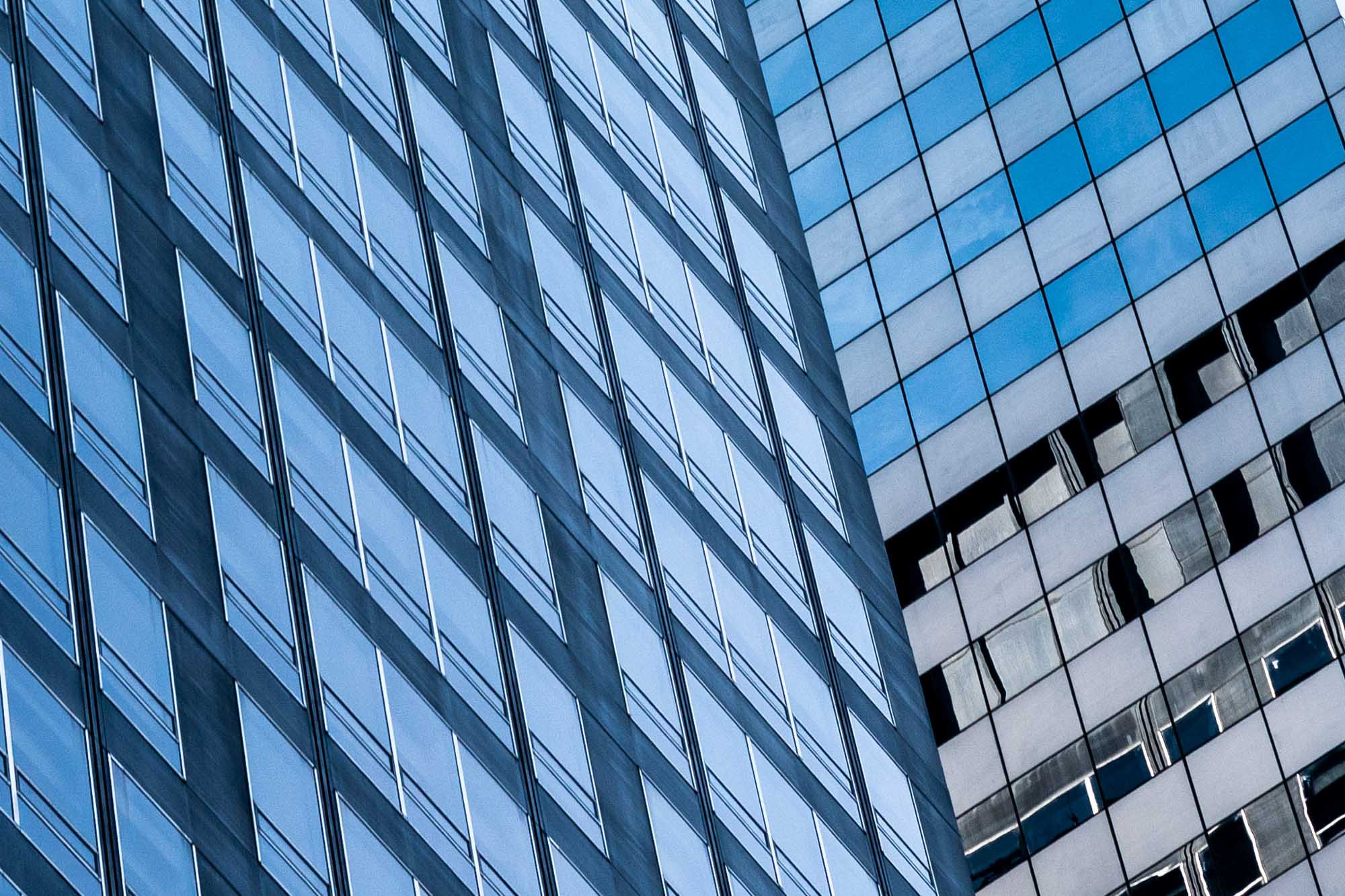 Diagonal view of two skyscrapers with reflective glass windows in a modern cityscape.