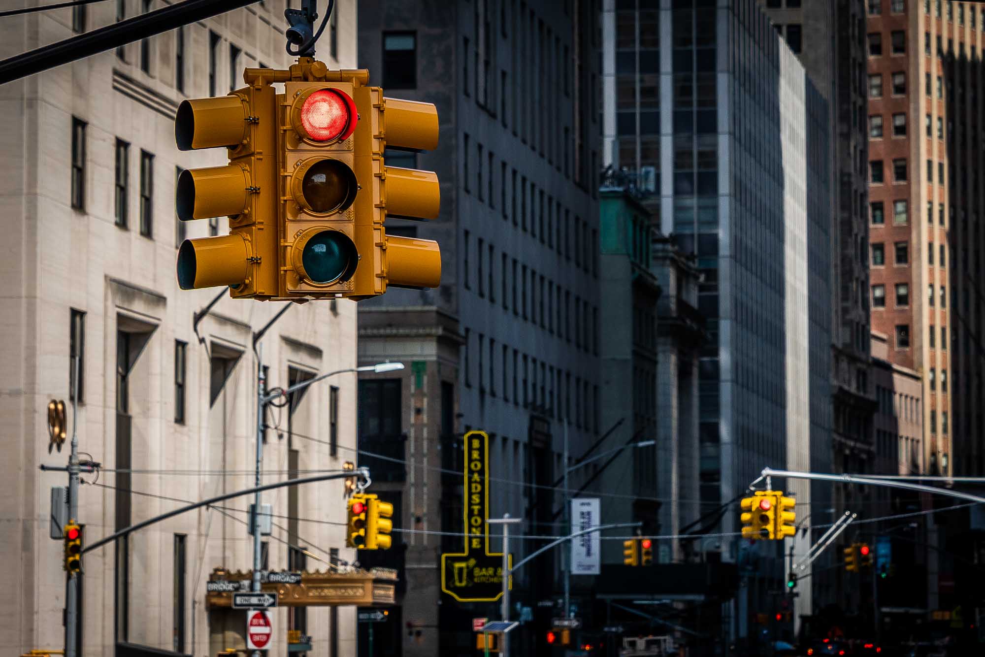 Traffic light showing red signal in a busy urban street with tall buildings in the background.