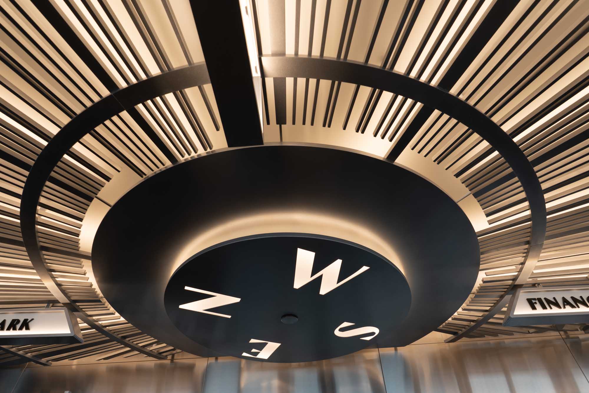 Modern ceiling compass design in metallic tones with directional letters N, E, S, W, and geometric patterns.