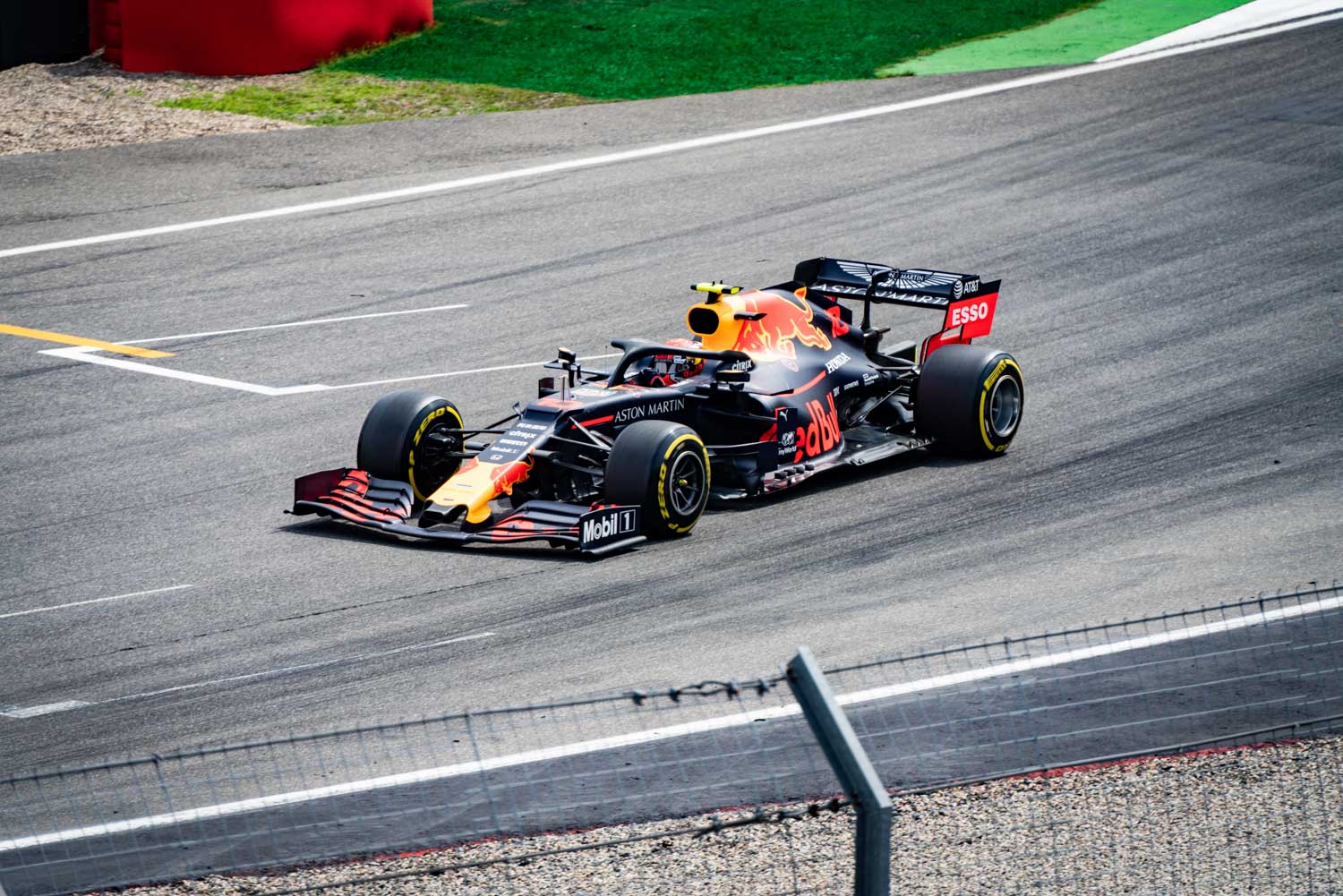 Formula 1 race car on track, featuring Red Bull and Aston Martin logos, speeding through a turn.