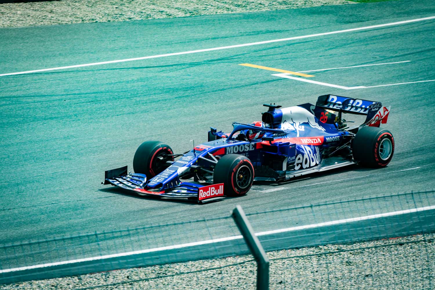 Blue Formula 1 car racing on track, featuring Red Bull and Honda branding, moving at high speed.