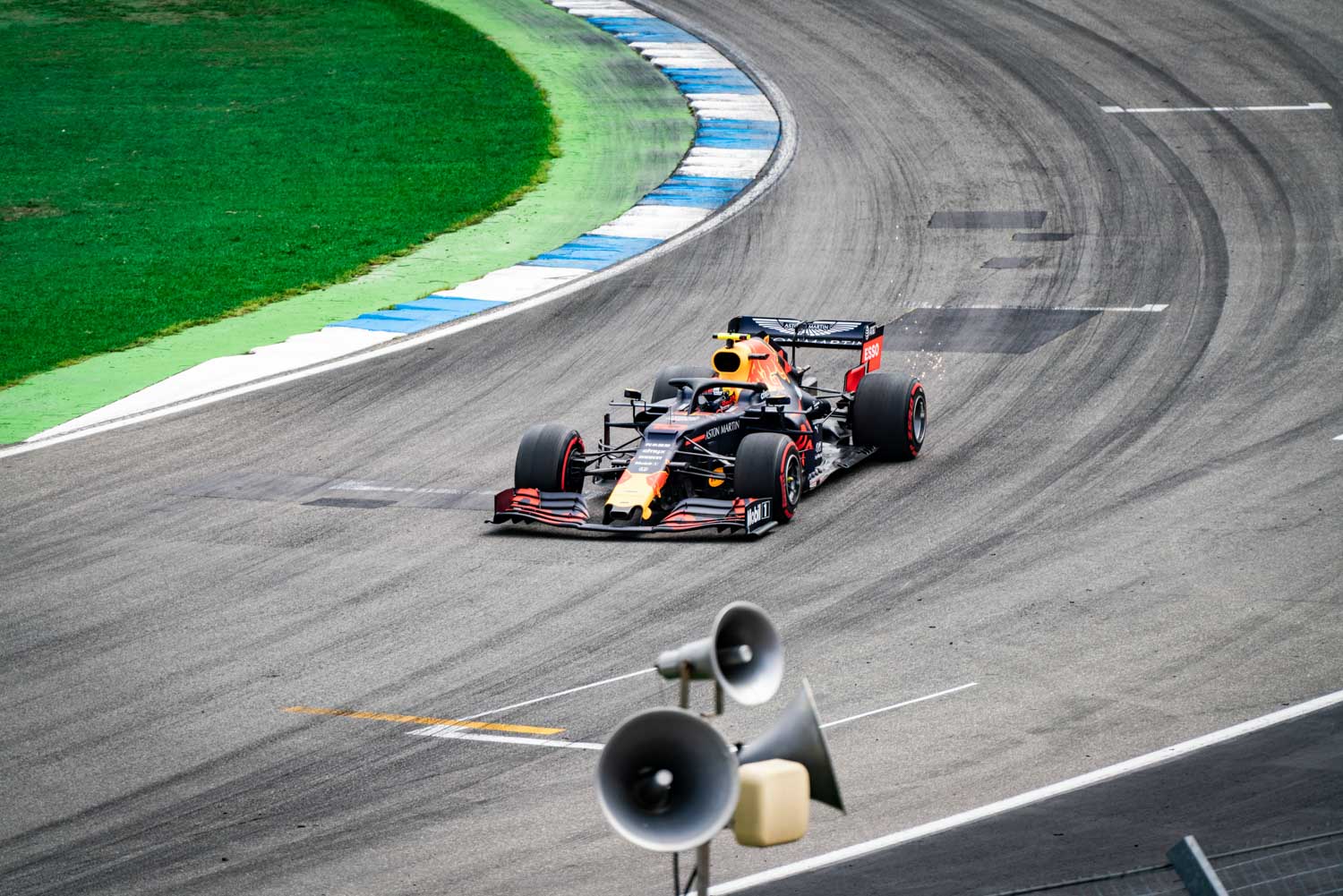 Race car speeding on the track at a motorsport event, with green grass and track barriers visible in the background.