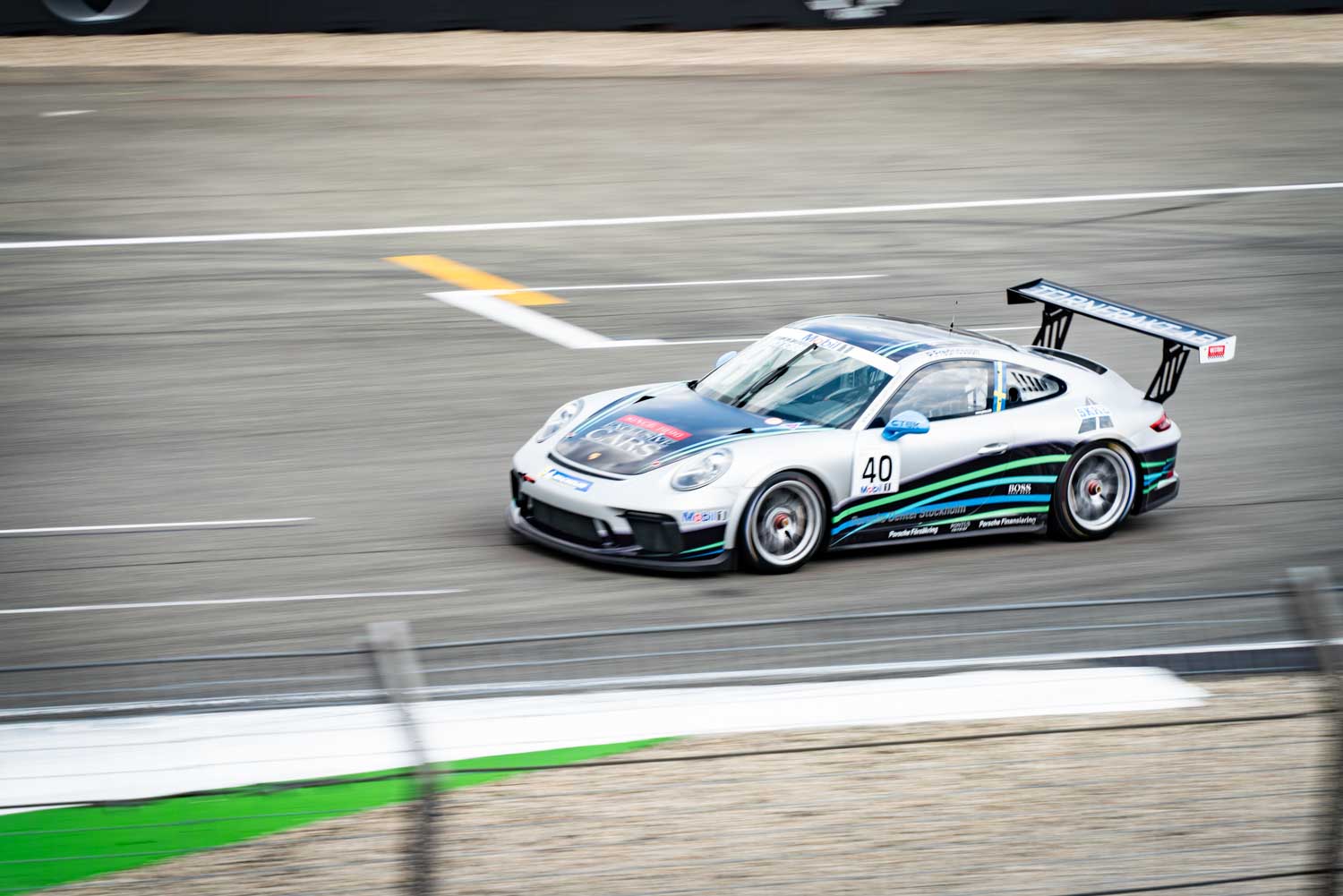 White race car with number 40 speeding on a racetrack, showcasing dynamic motion and sleek design.