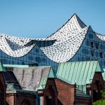 Modern wavy glass architecture of the Elbphilharmonie building in Hamburg with a clear blue sky.