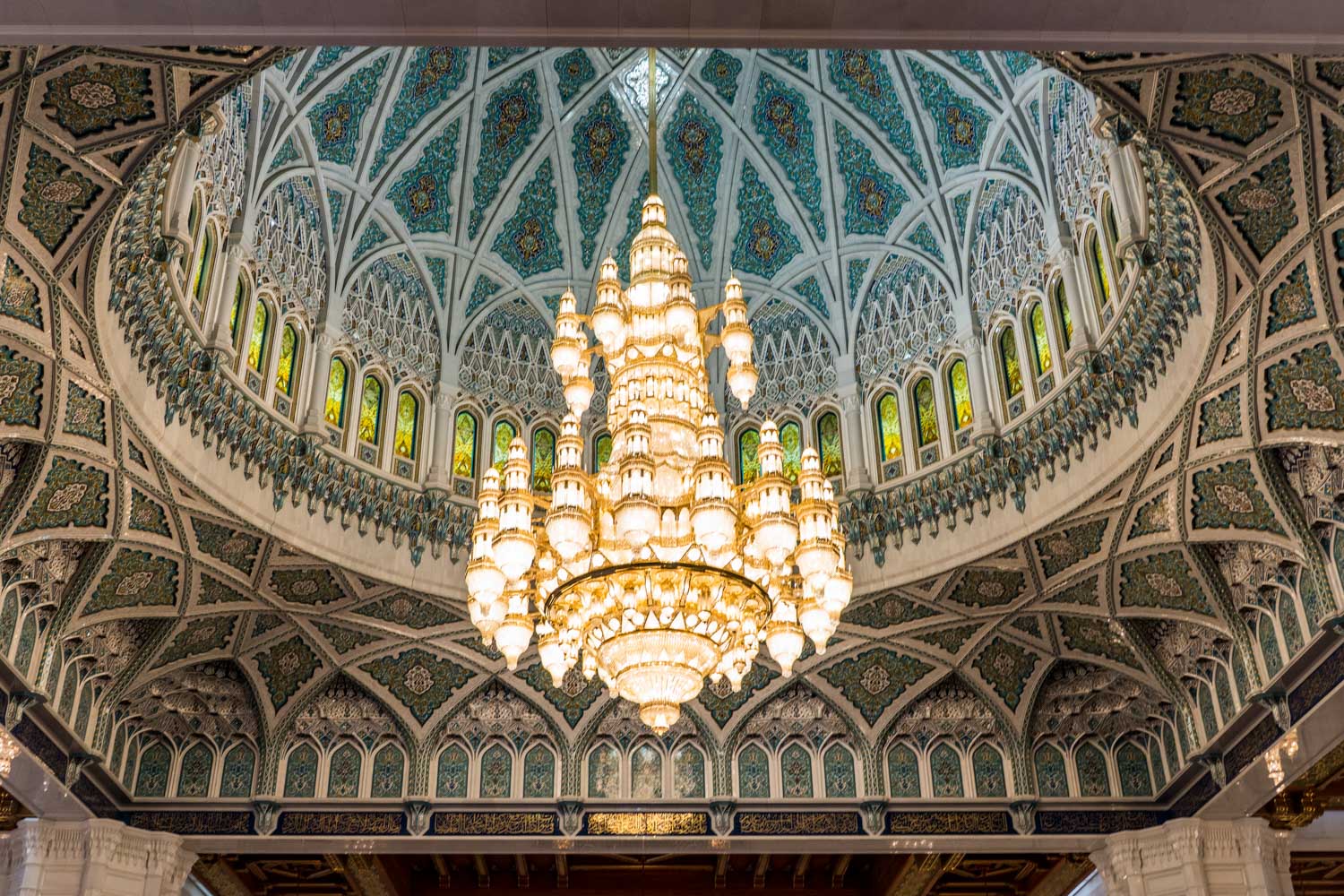 Intricate Islamic dome interior featuring ornate design and a large central chandelier.