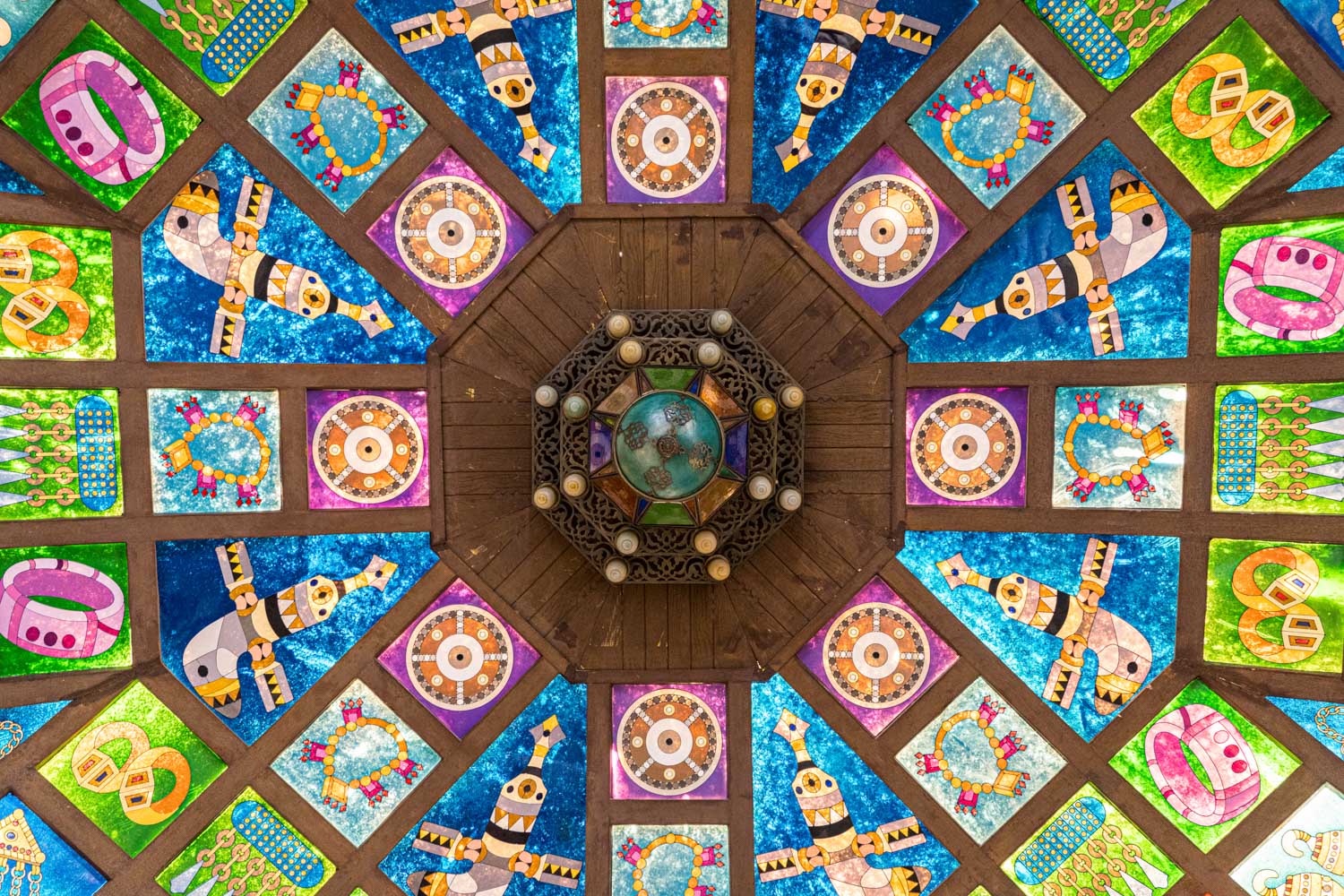 Colorful geometric stained glass ceiling with intricate patterns and a decorative central wooden structure.