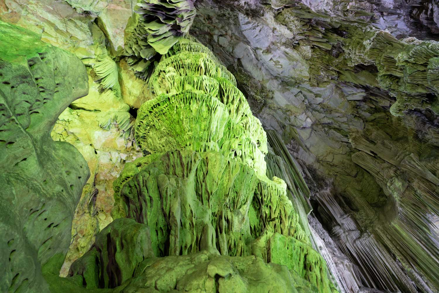 Intricate green rock formations inside a cave with natural textures and unique patterns.