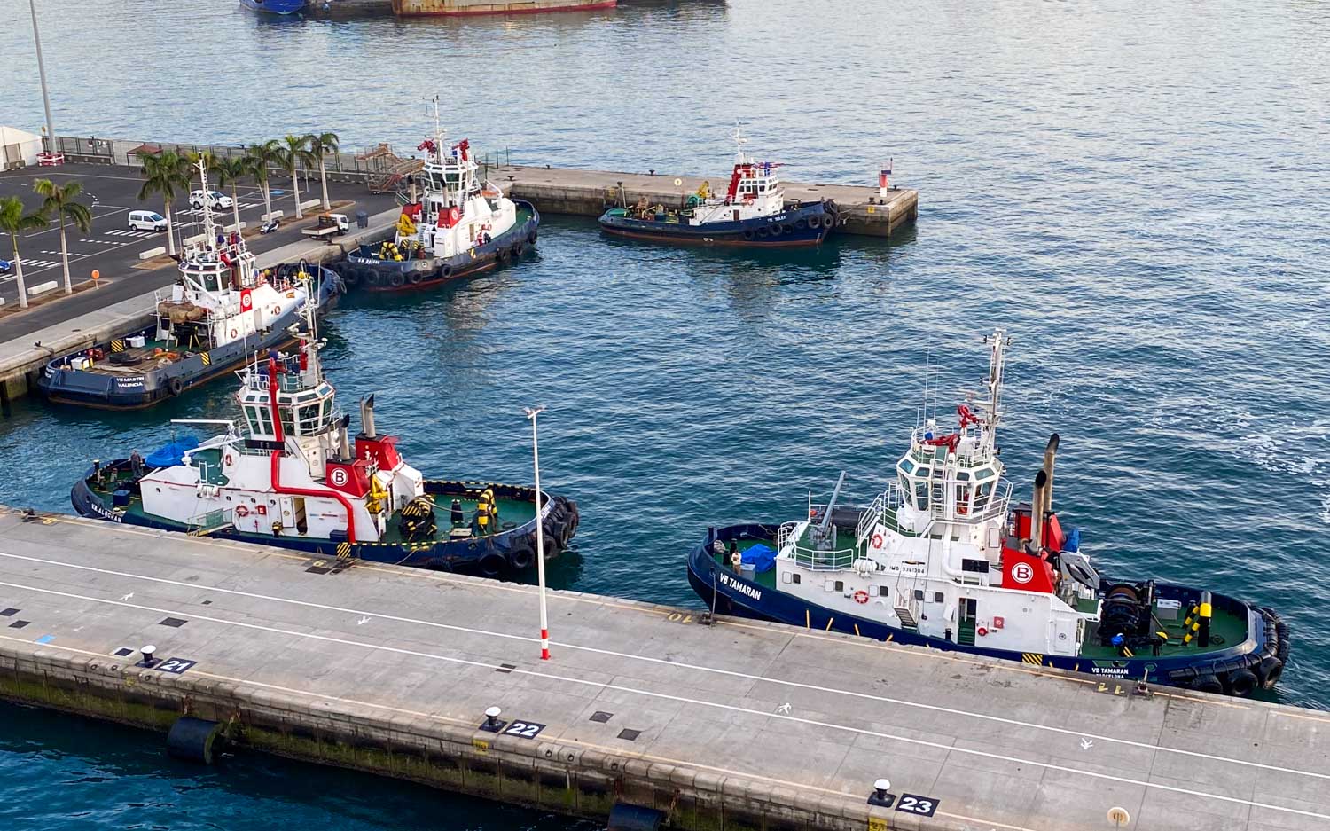 Tugboats moored at a busy harbor pier, ready for maritime operations.