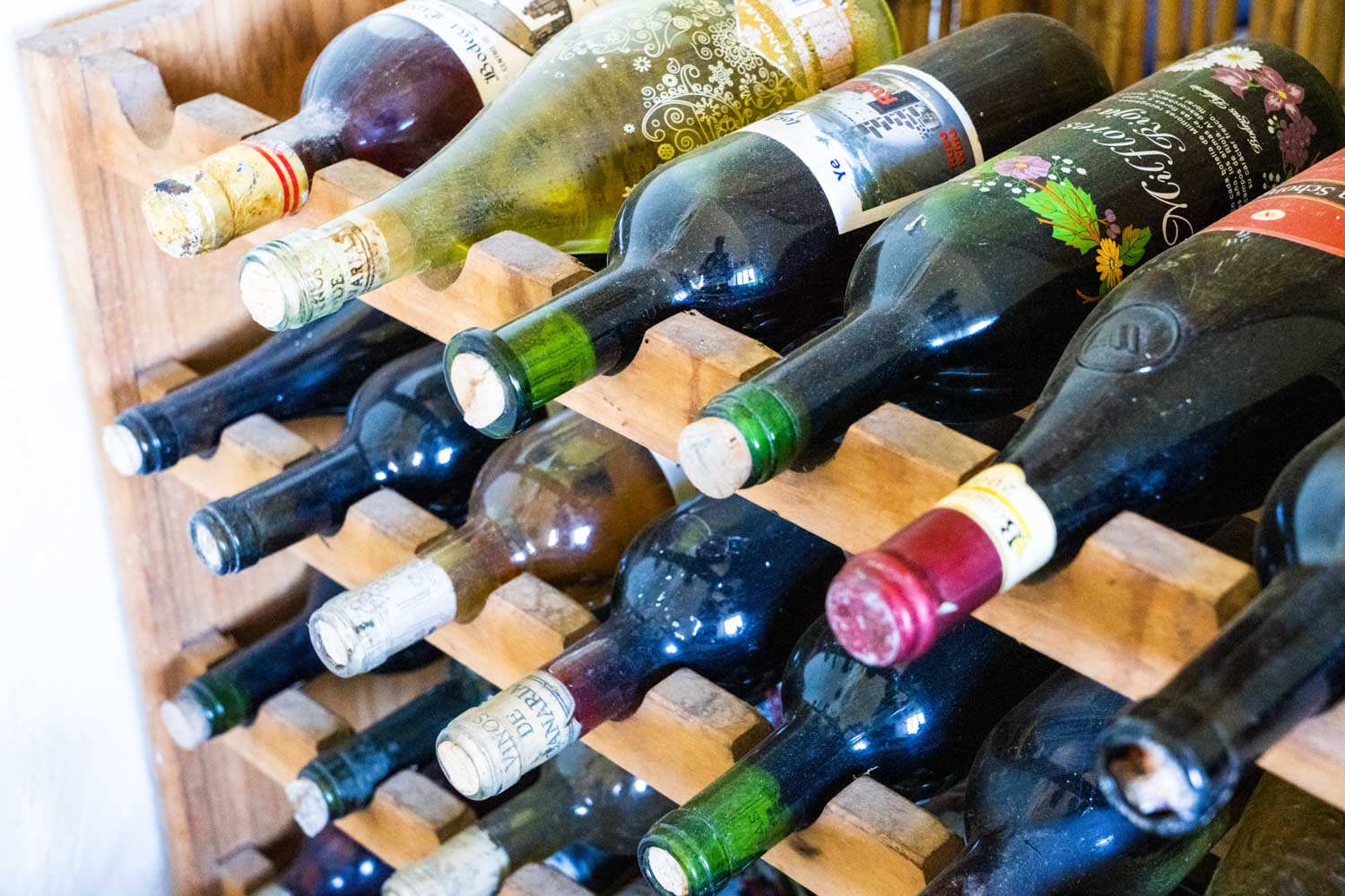 Wooden wine rack filled with assorted wine bottles, showcasing a variety of labels and colors.