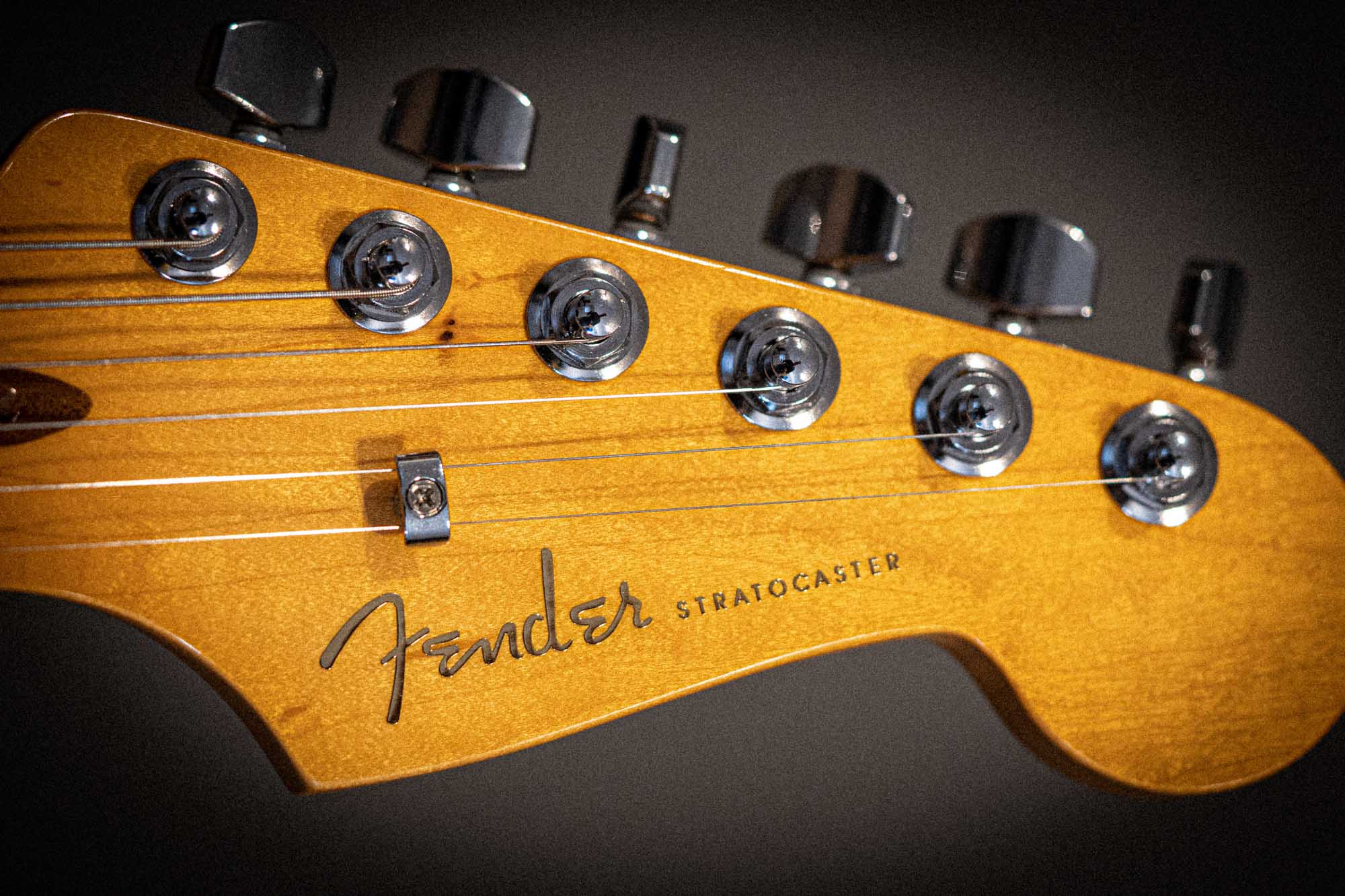 Close-up of a Fender Stratocaster guitar headstock with tuning pegs and logo.