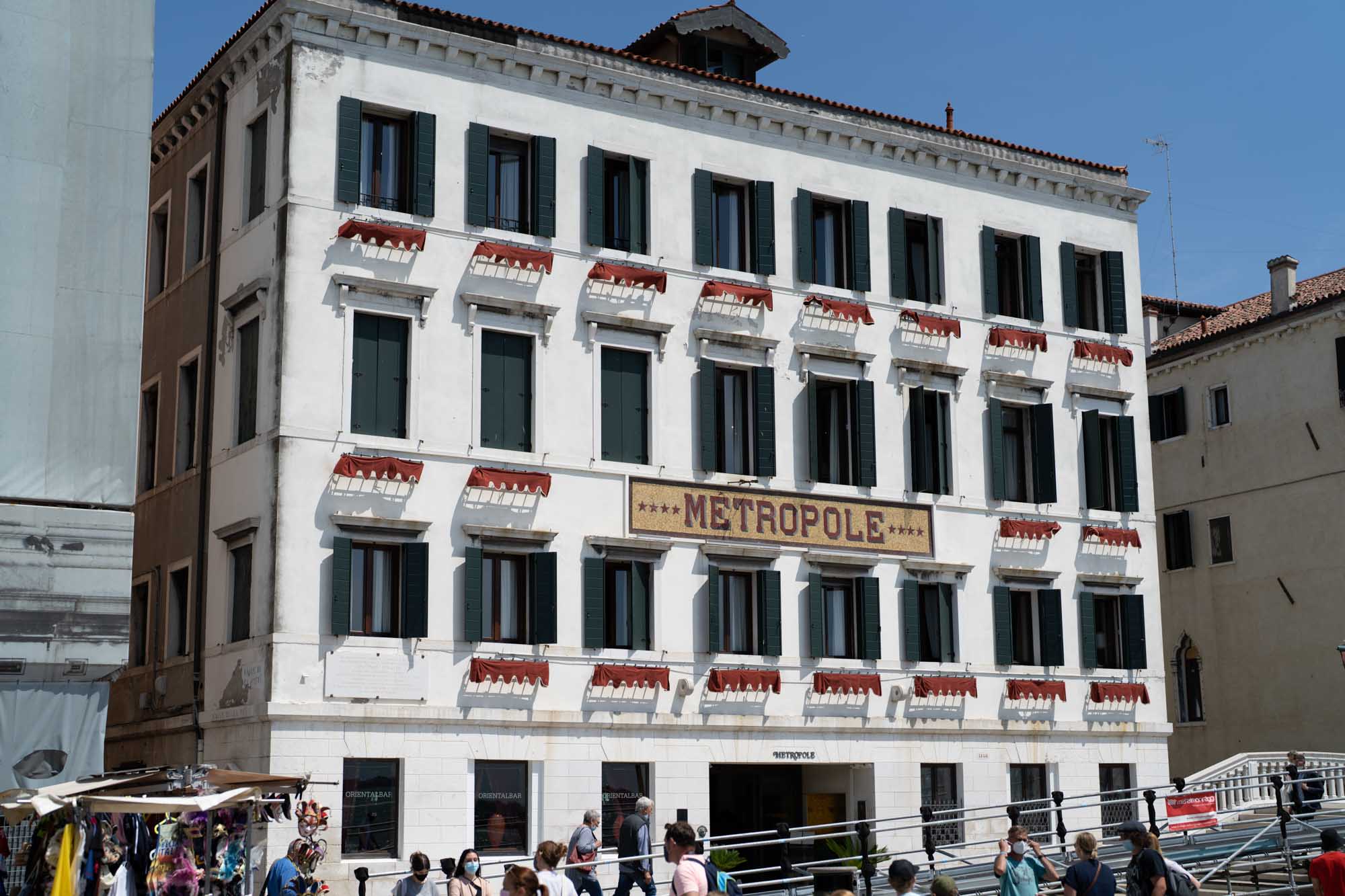 Historic Metropole Hotel in Venice with people walking in front, sunny day.