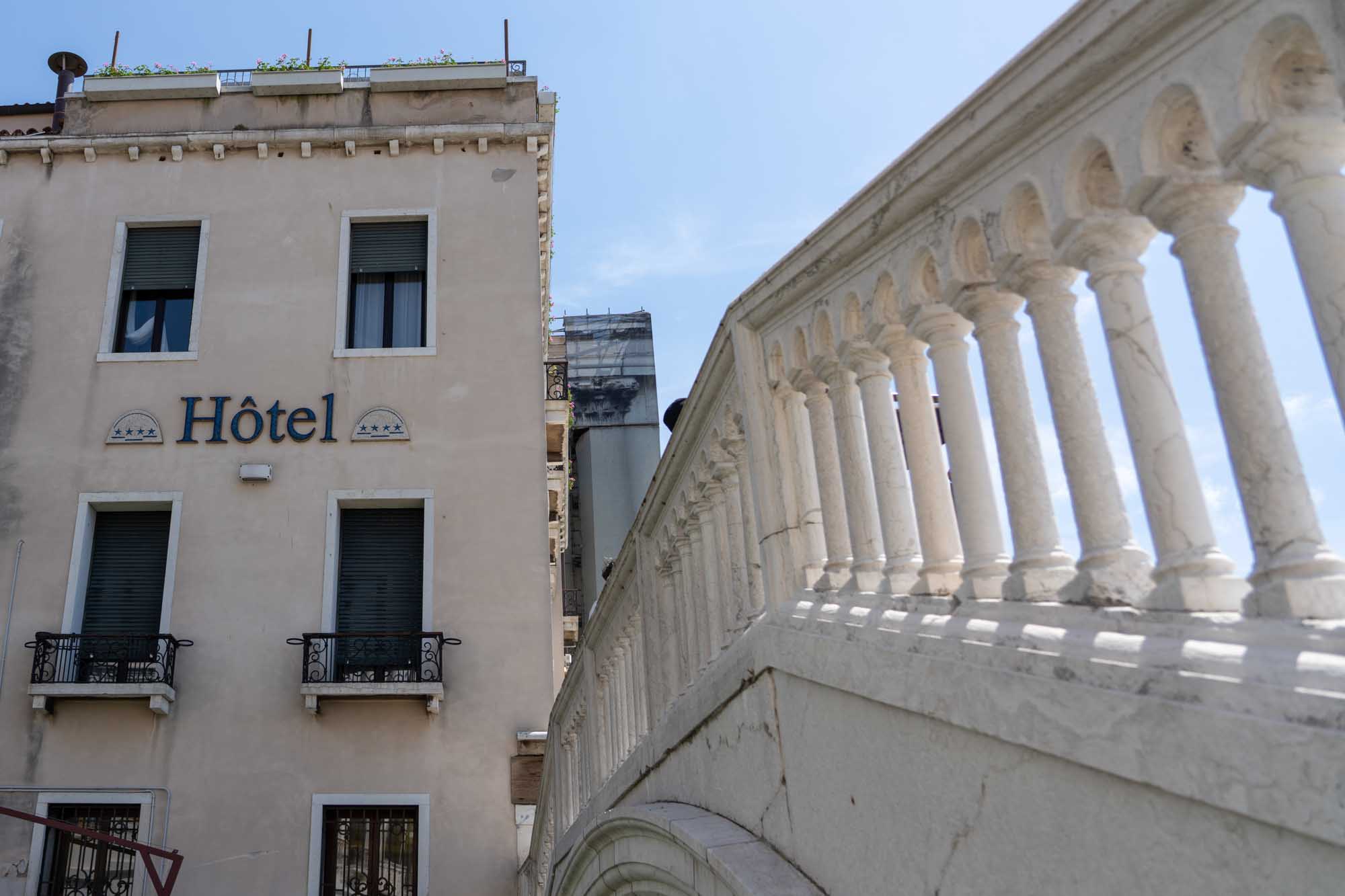 Historic hotel facade beside ornate stone balustrade under a clear blue sky.