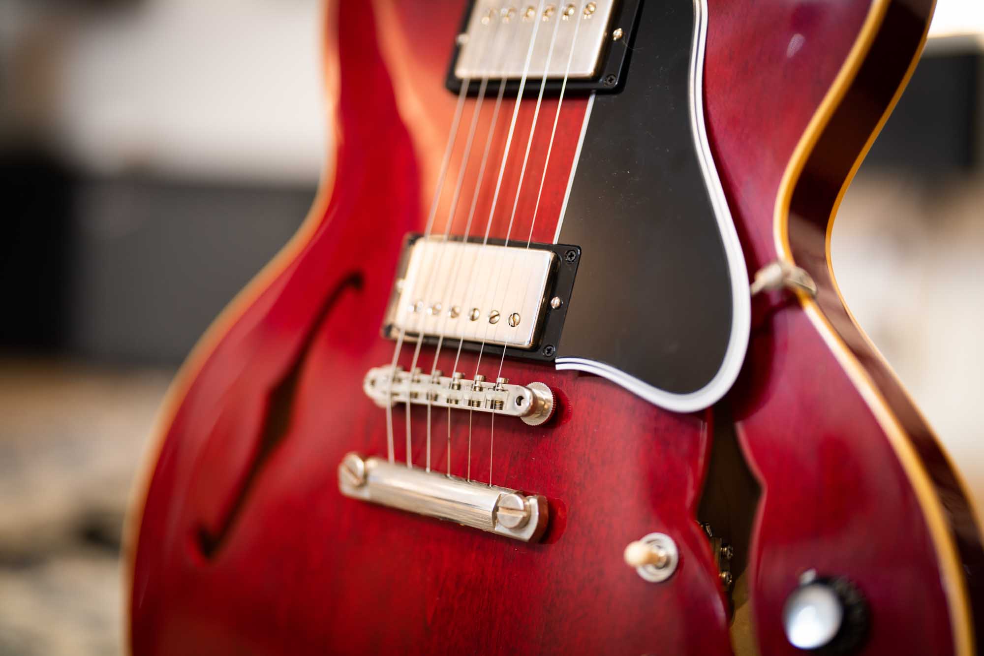 Close-up of a red semi-hollow electric guitar with visible strings and pickups.