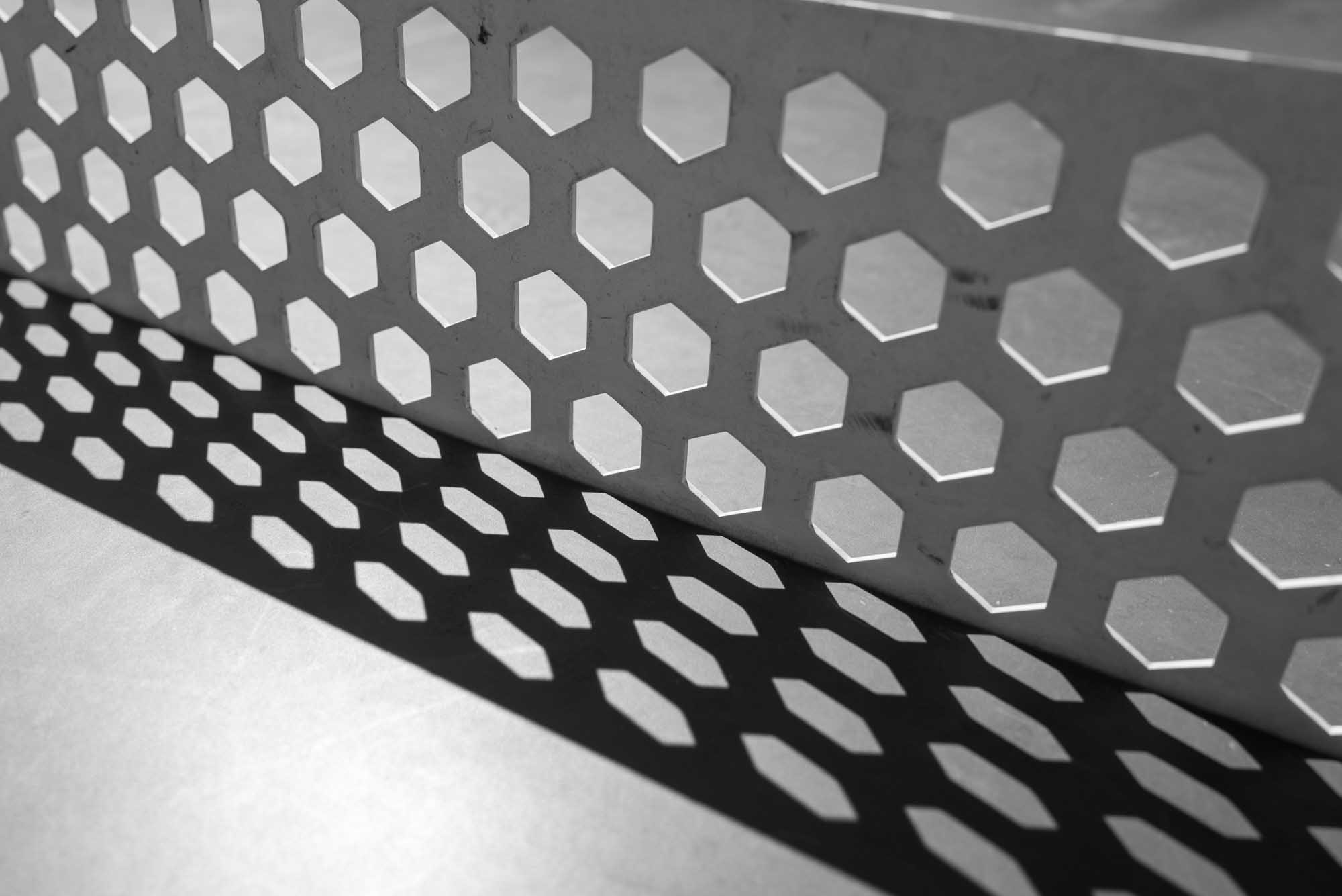 Hexagonal pattern casting shadow on surface in black and white.