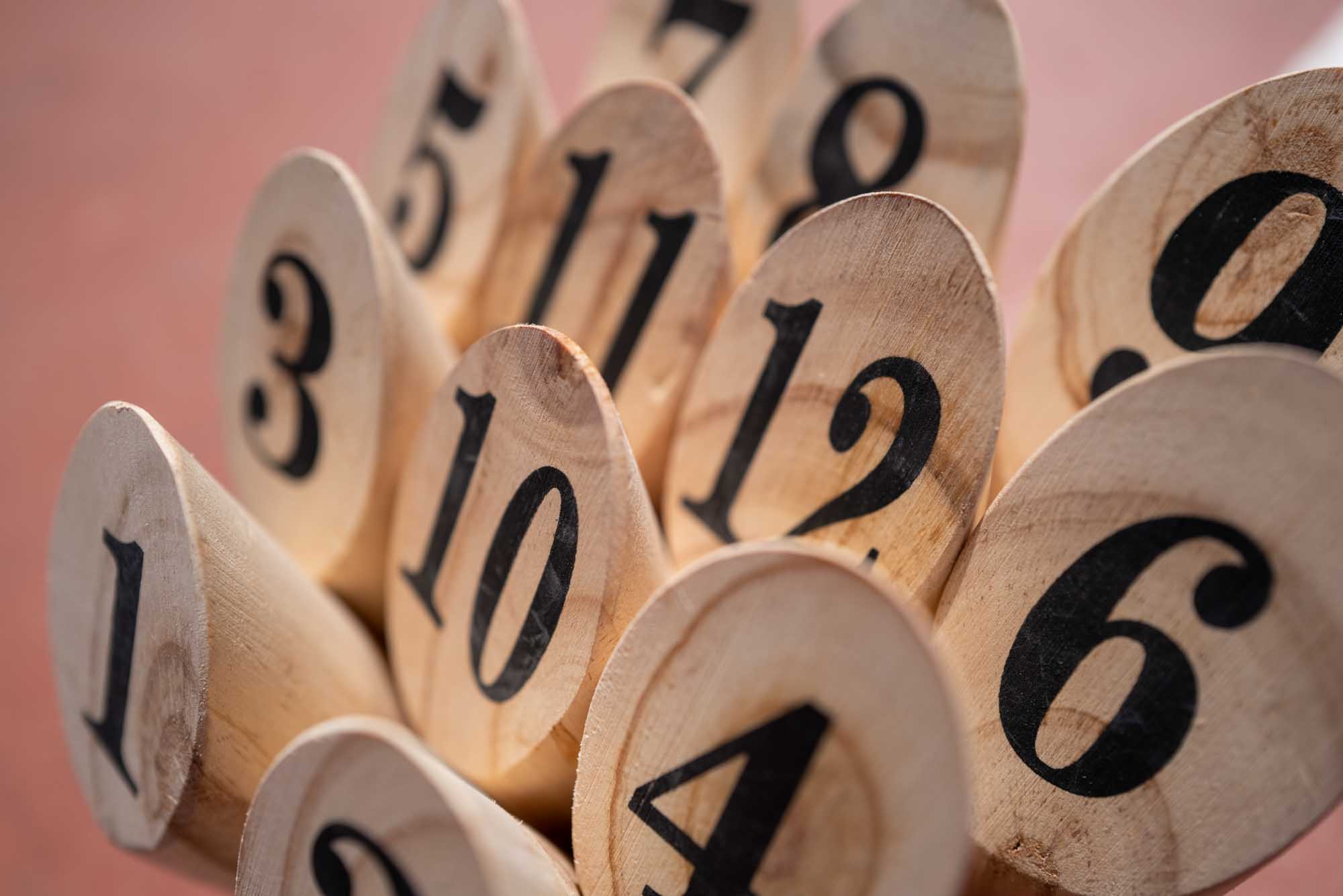 Wooden pegs with black numbers arranged closely, displaying numbers 1 to 12 on a blurred background.