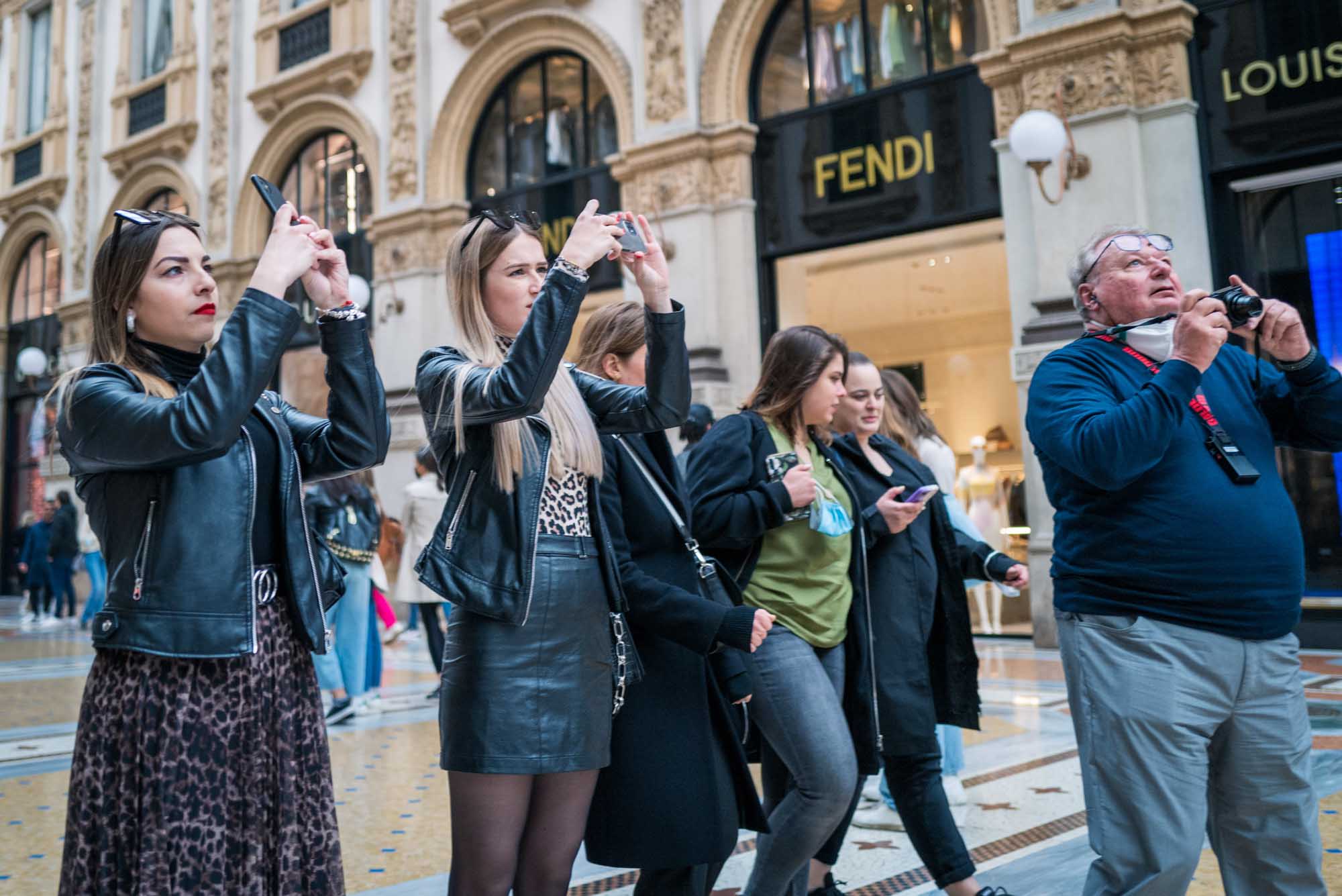People taking photos inside a luxurious mall, with Fendi storefront in the background.