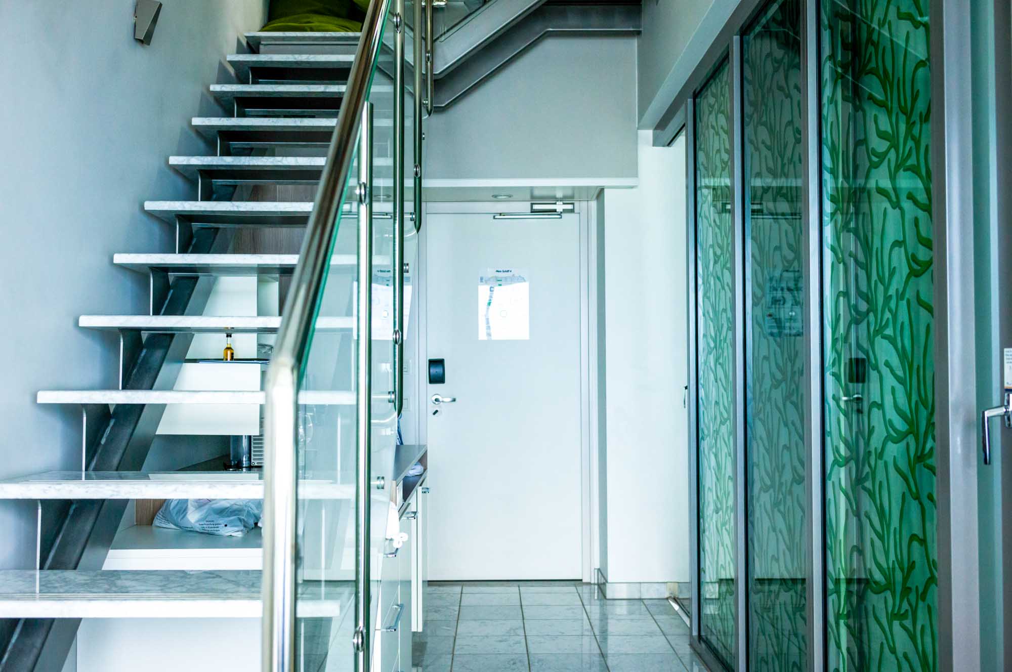 Modern interior with a sleek staircase and glass doors featuring green leaf patterns.