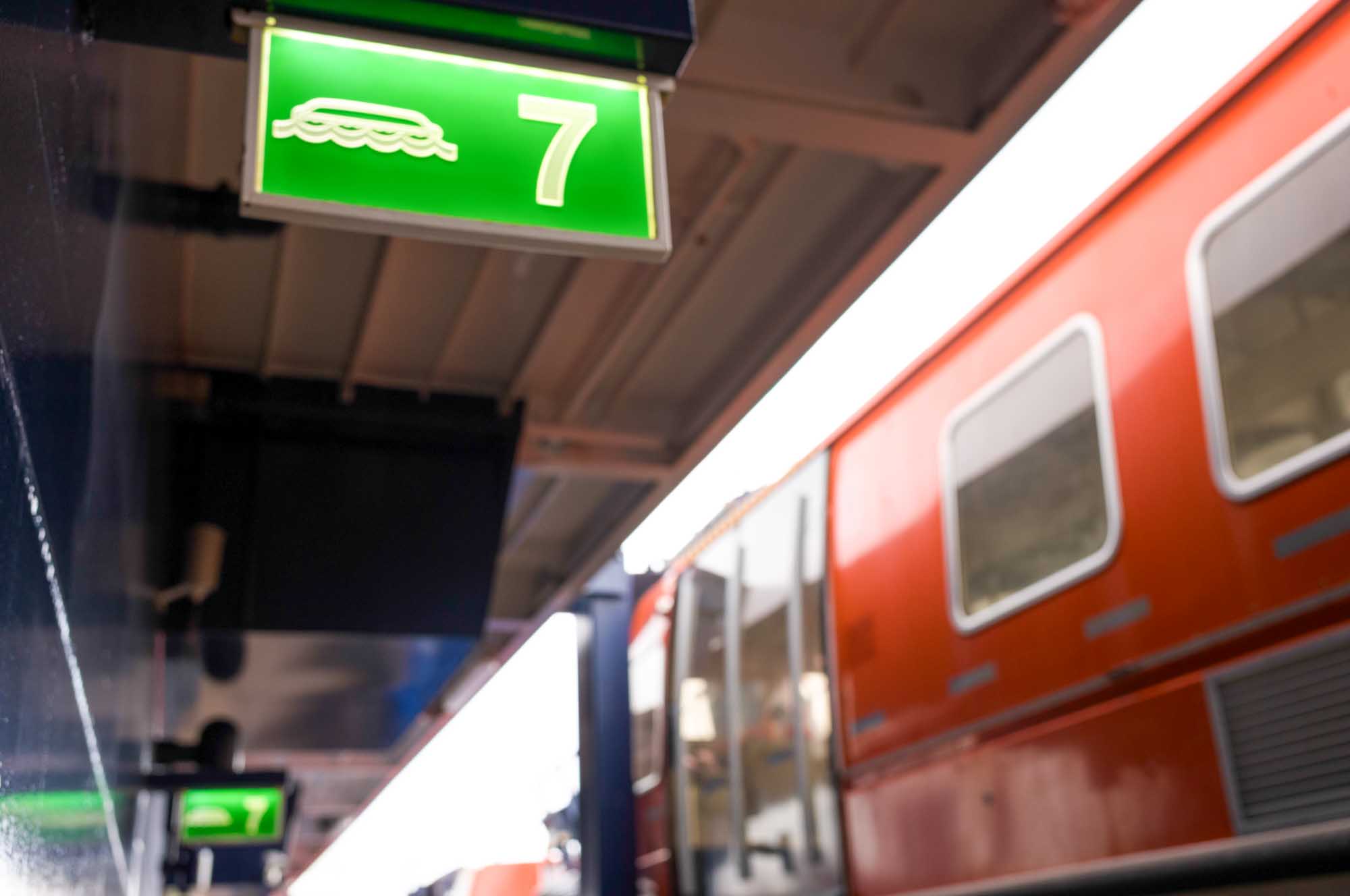 Train platform with sign for line 7 and an orange train in the station.