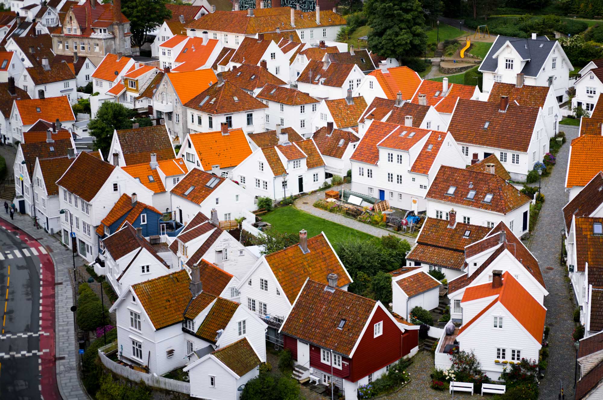 Aerial view of traditional white houses with red roofs clustered in a scenic European village neighborhood.