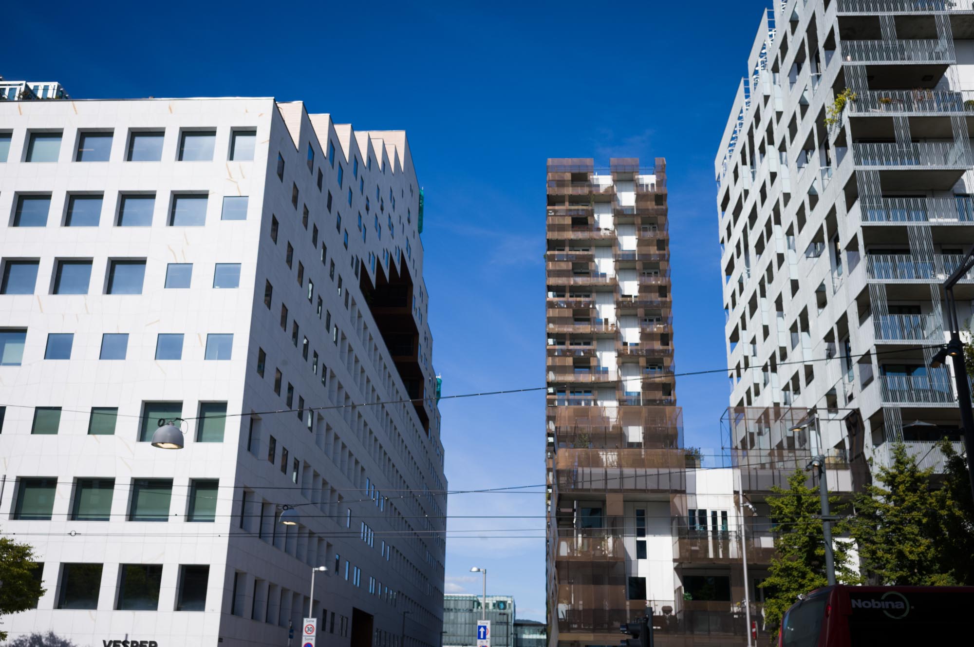 Modern cityscape with three unique skyscrapers under a clear blue sky.