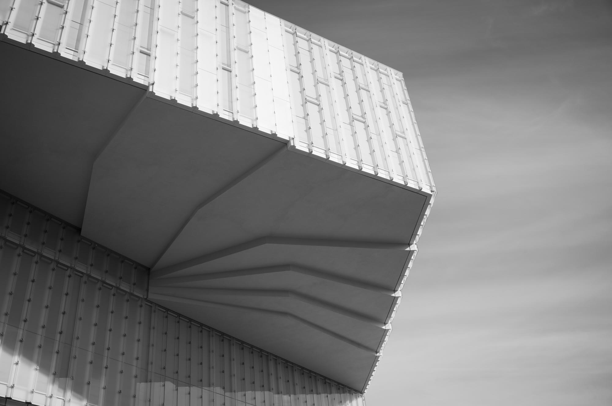 Modern architectural facade with geometric patterns and glass panels, captured in black and white.