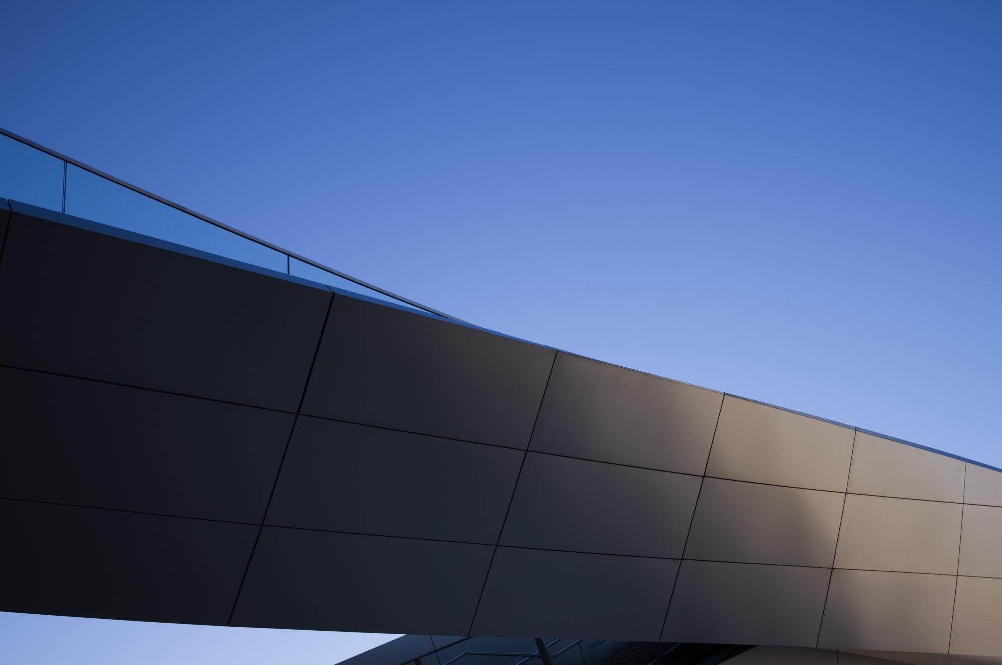 Modern architectural bridge against clear blue sky.