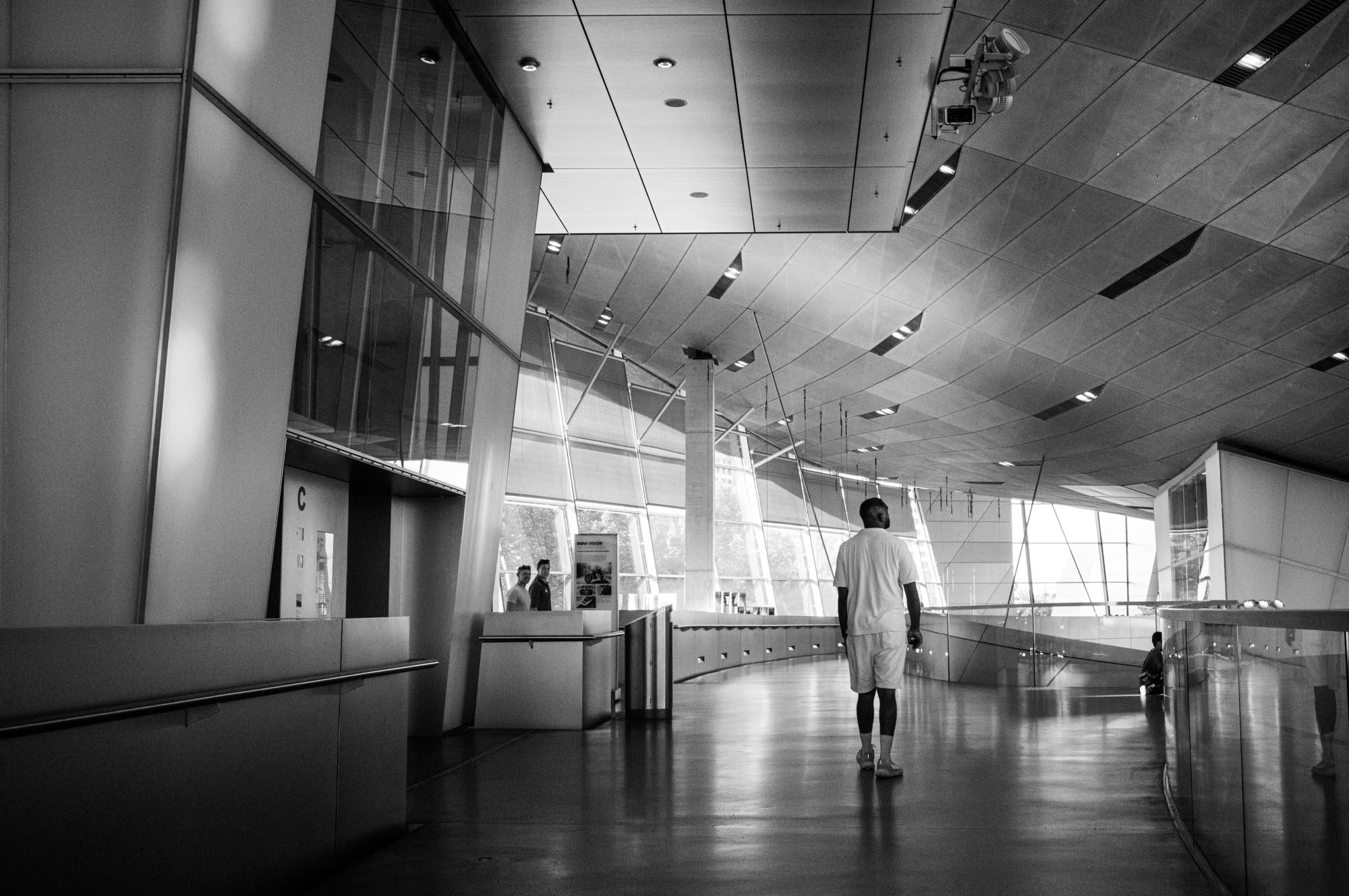 Modern architecture interior with person walking, sleek design and large windows, black and white photography.