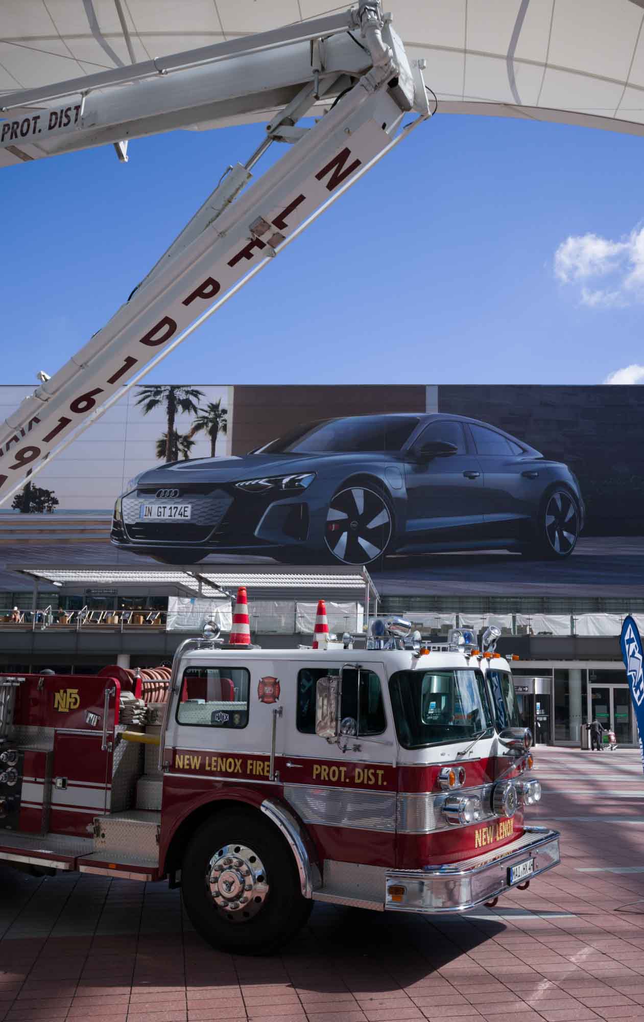 Fire truck in front of large Audi car billboard on a sunny day with clear sky.