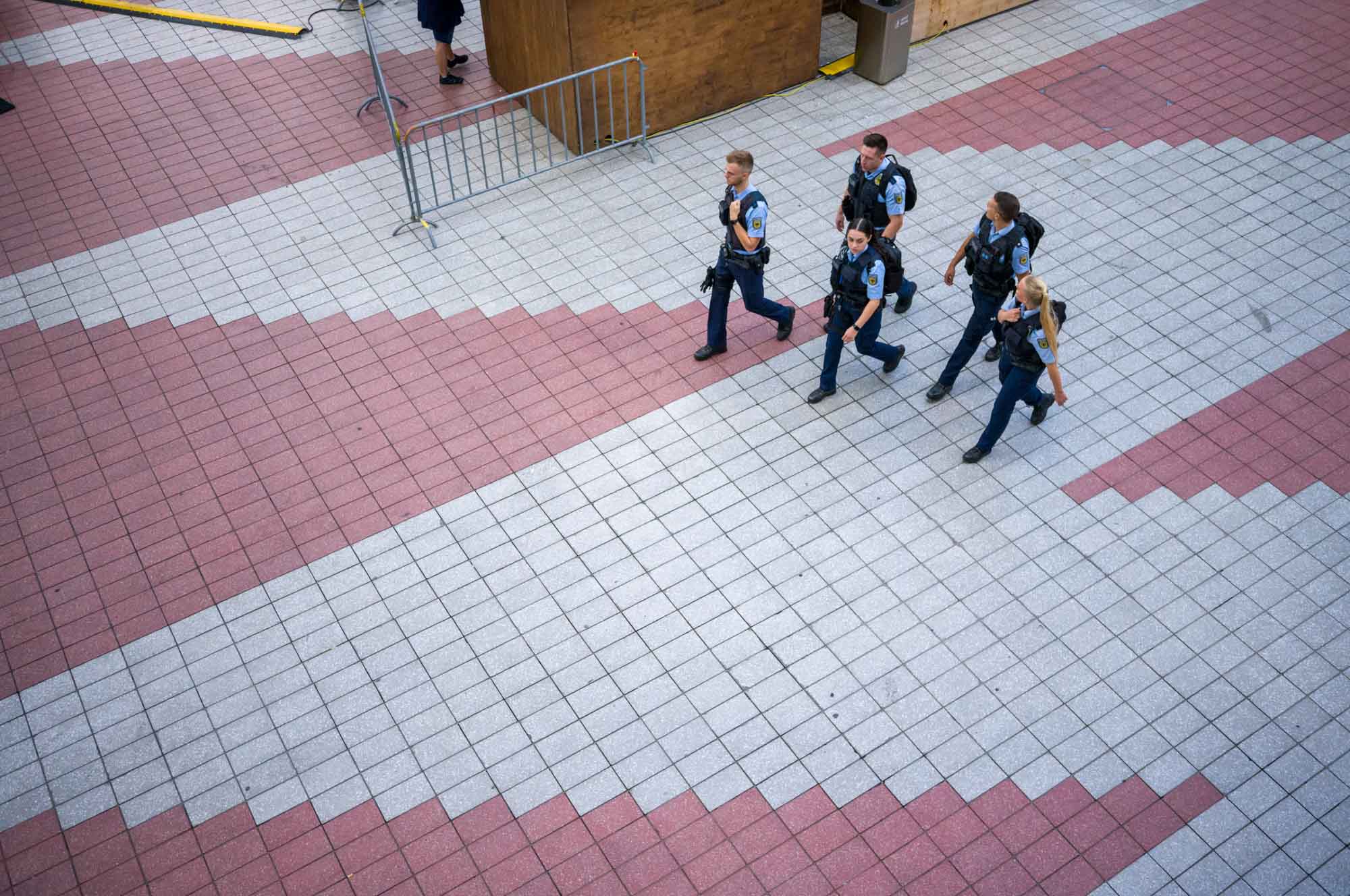 Group of police officers walking on a tiled path, viewed from above.