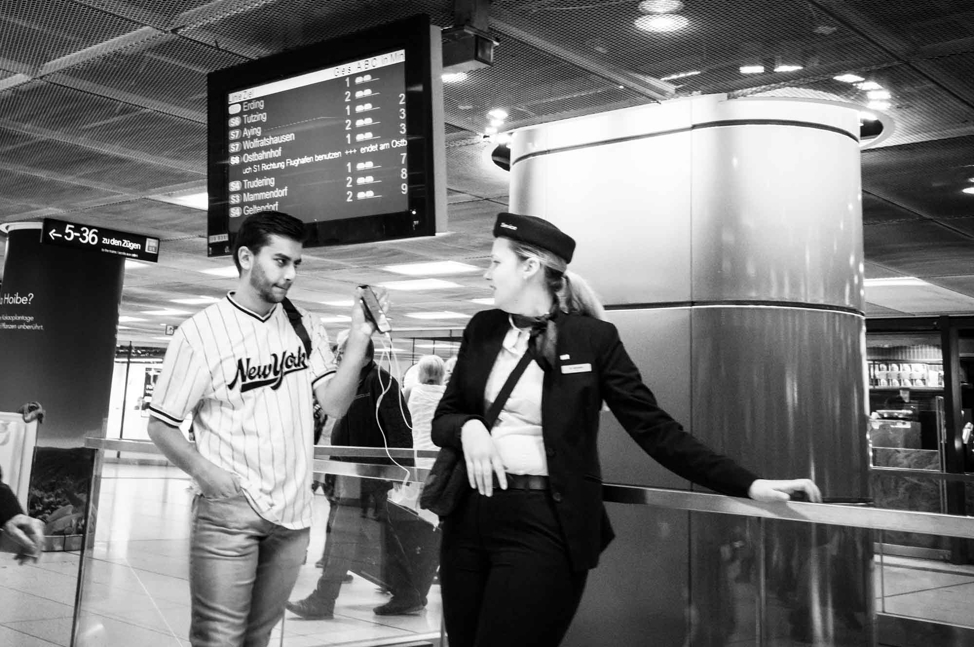 Man and woman interacting at a transit station with signage and directions visible above them.