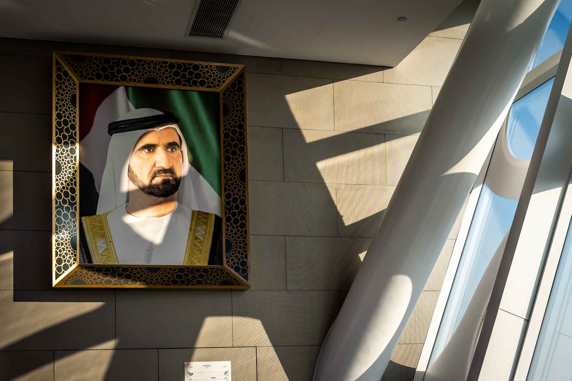 Framed portrait of a man under sunlight in modern building interior with architectural shadows.