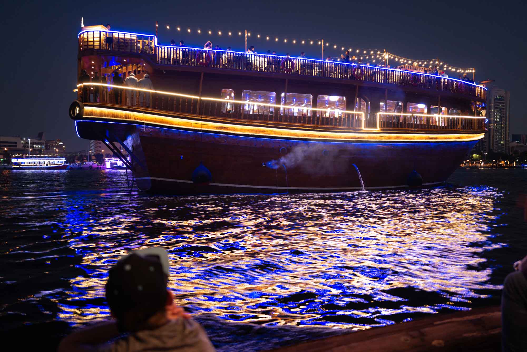 Luxurious evening cruise on lit-up boat reflecting on water at city harbor.