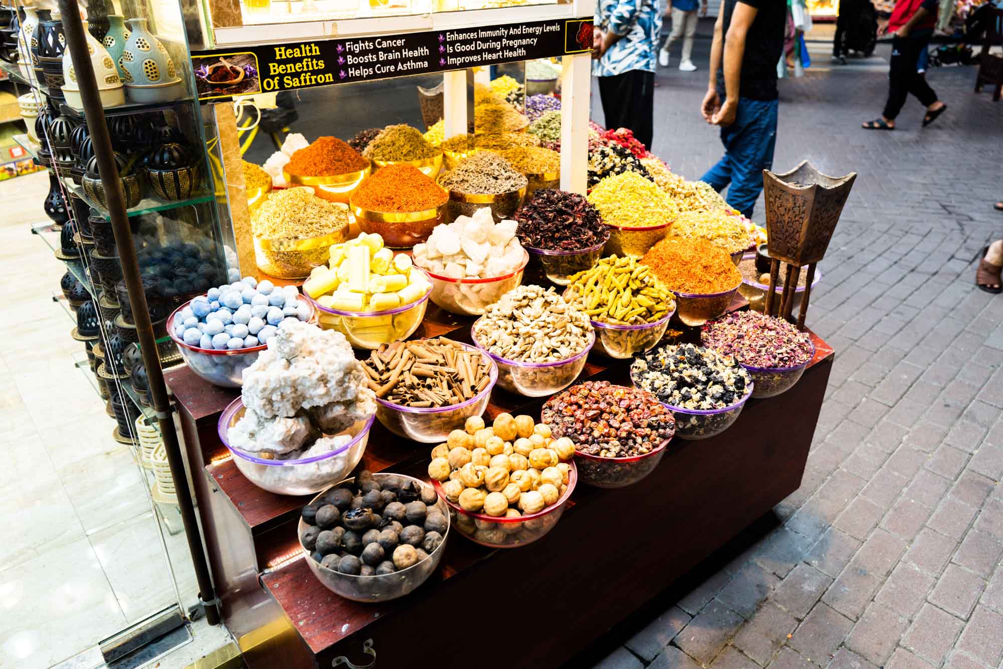 Colorful spice display at a bustling market, showcasing diverse herbs and spices in vibrant bowls.