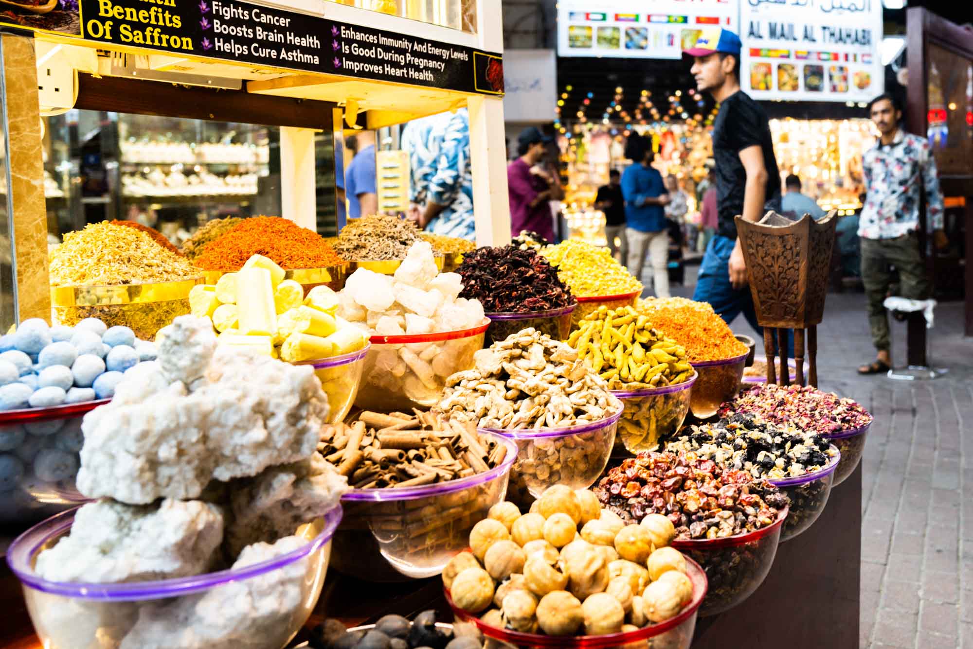 Variety of colorful spices on display at a bustling market, showcasing saffron and other vibrant ingredients.