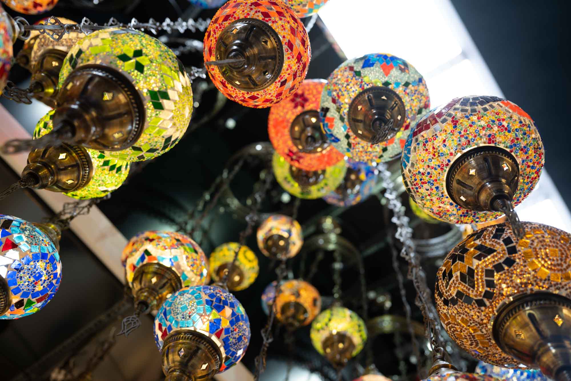 Vibrant mosaic glass lanterns hanging from the ceiling, creating colorful and artistic lighting.