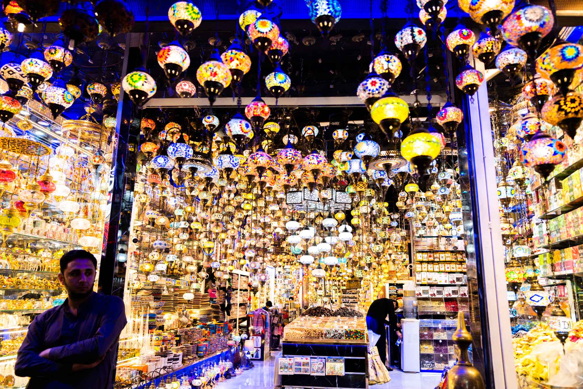 Colorful lamps and goods displayed in a vibrant Middle Eastern market stall at night.