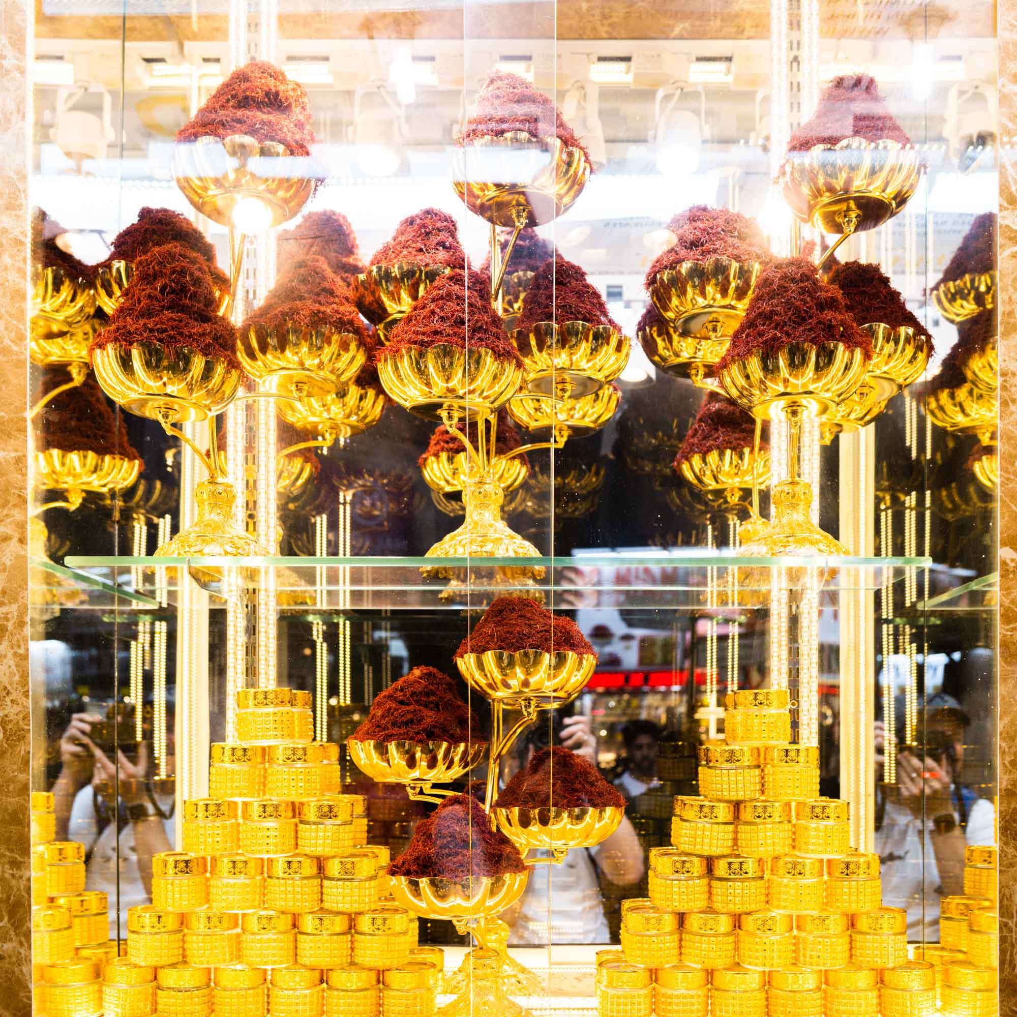 Luxurious saffron display in gold bowls and coin stacks reflecting opulence and wealth in a shop window.