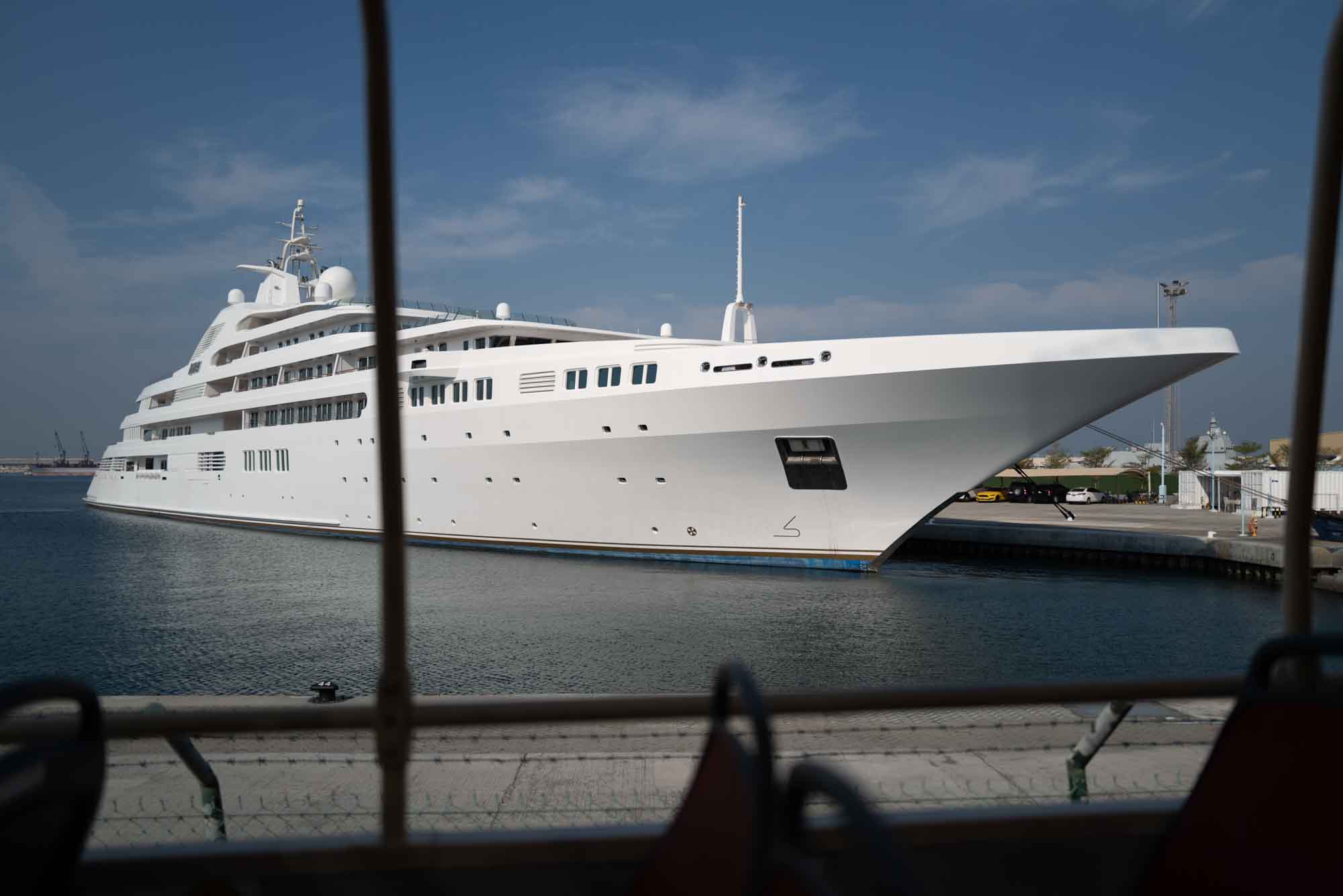 Luxurious white yacht docked at a harbor on a sunny day, showcasing its sleek design and multiple decks.