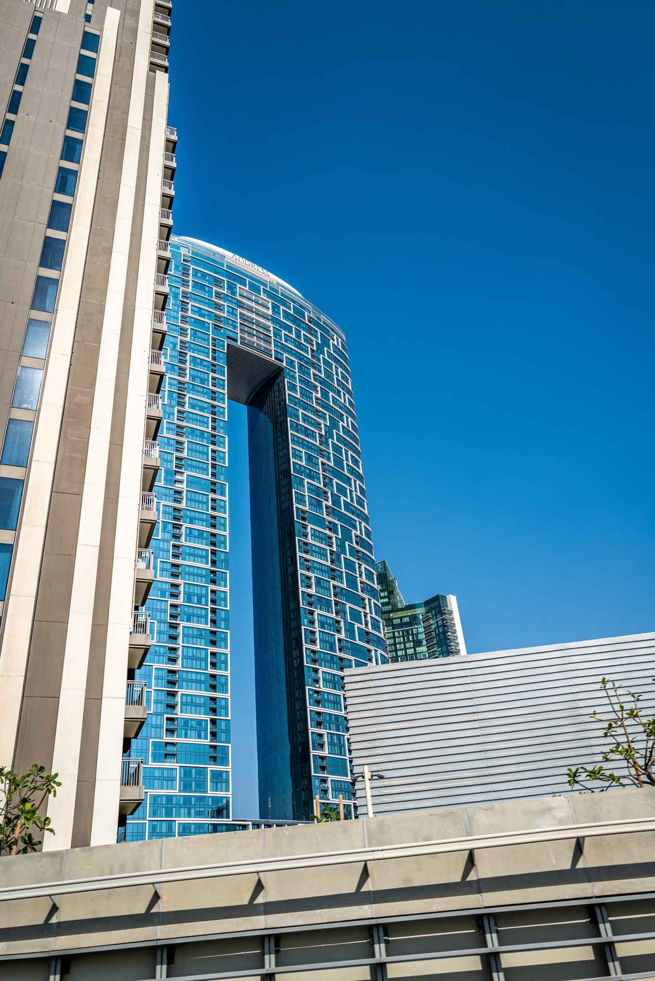 Modern skyscraper with unique design and blue-tinted windows against clear sky. Urban architecture and cityscape.