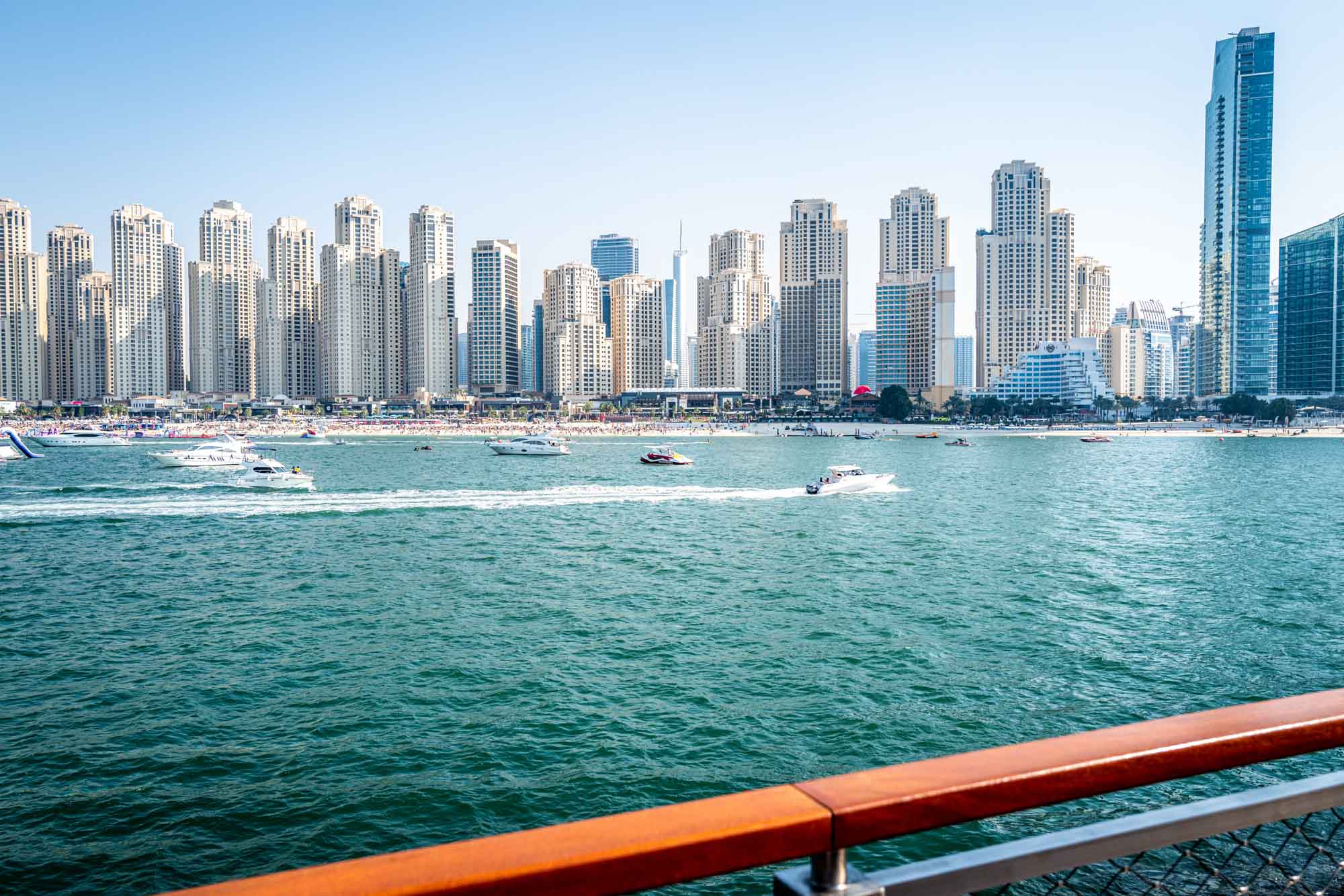 Skyline of modern skyscrapers and boats on blue water in Dubai Marina, showing urban and coastal lifestyle.