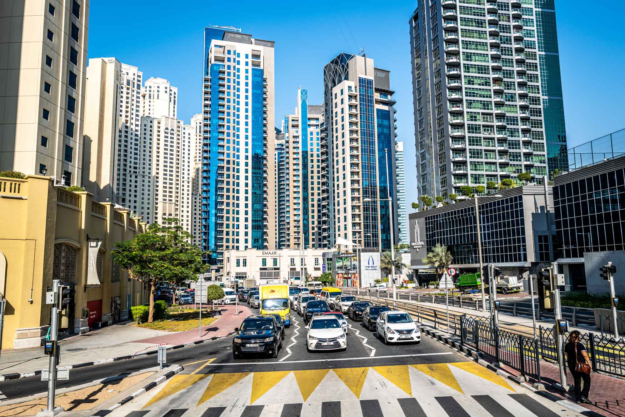 Skyscrapers and busy city street with traffic in modern urban area under clear blue sky.