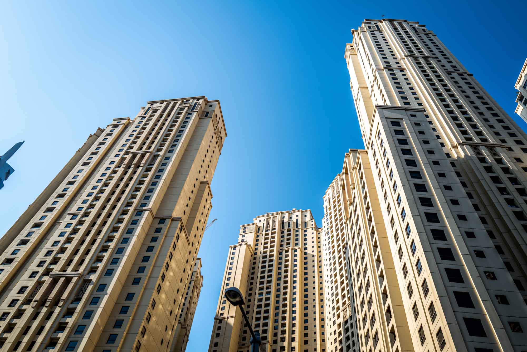 Skyscrapers against a clear blue sky in an urban setting, viewed from below.