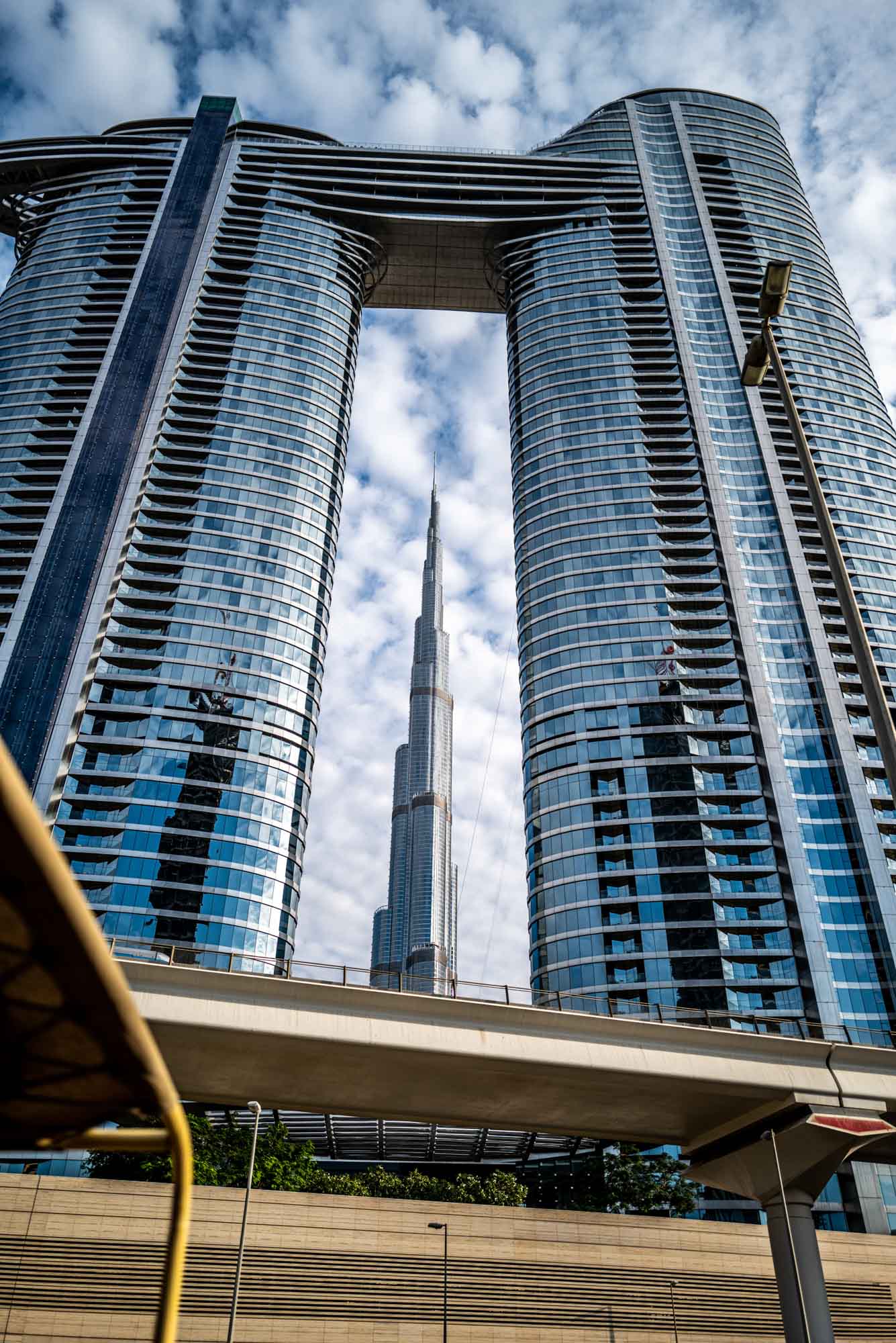 Modern skyscraper with a glass facade and unique architecture in a cityscape with a cloudy sky background.