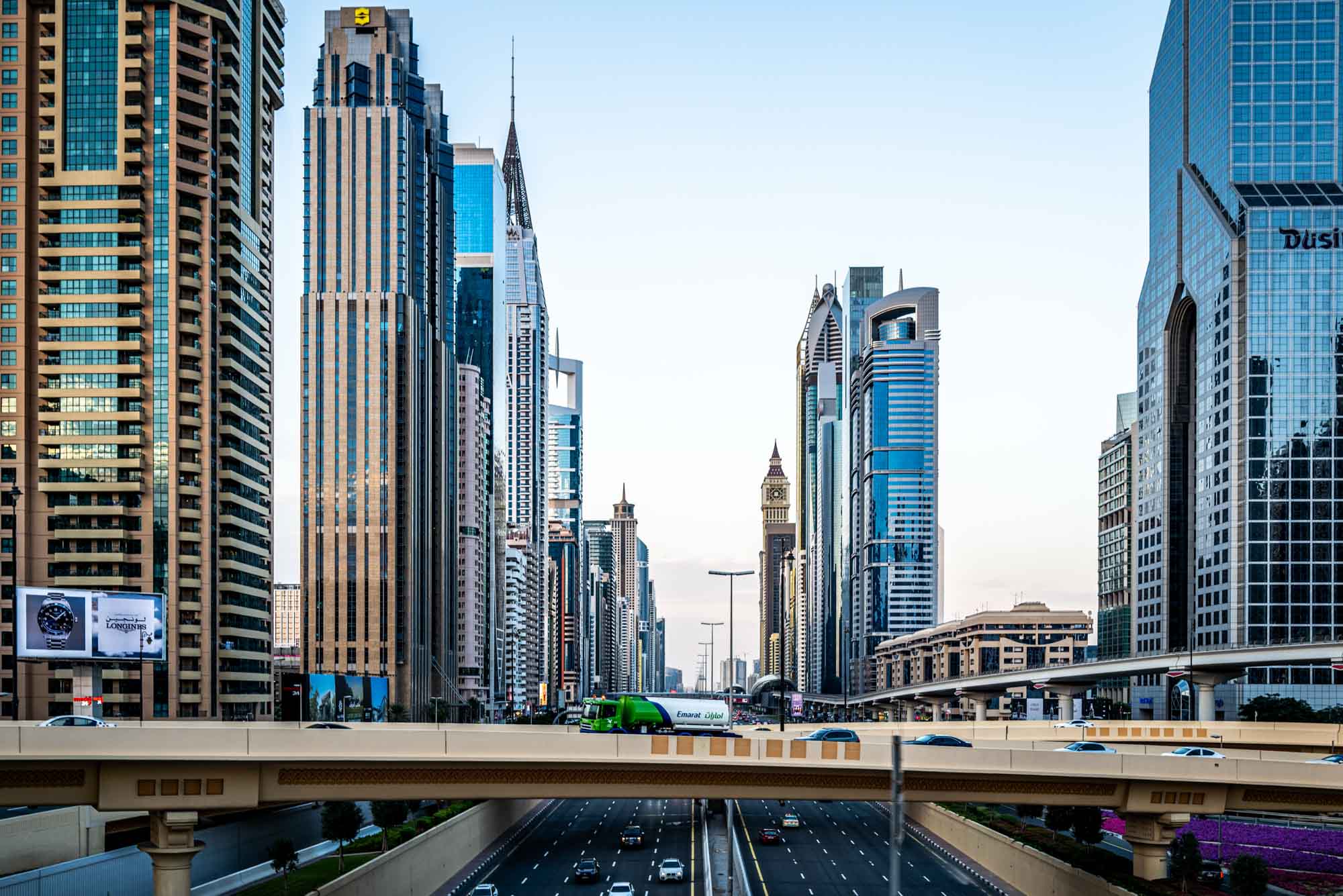 Modern Dubai cityscape with busy highway and towering skyscrapers under a clear blue sky.
